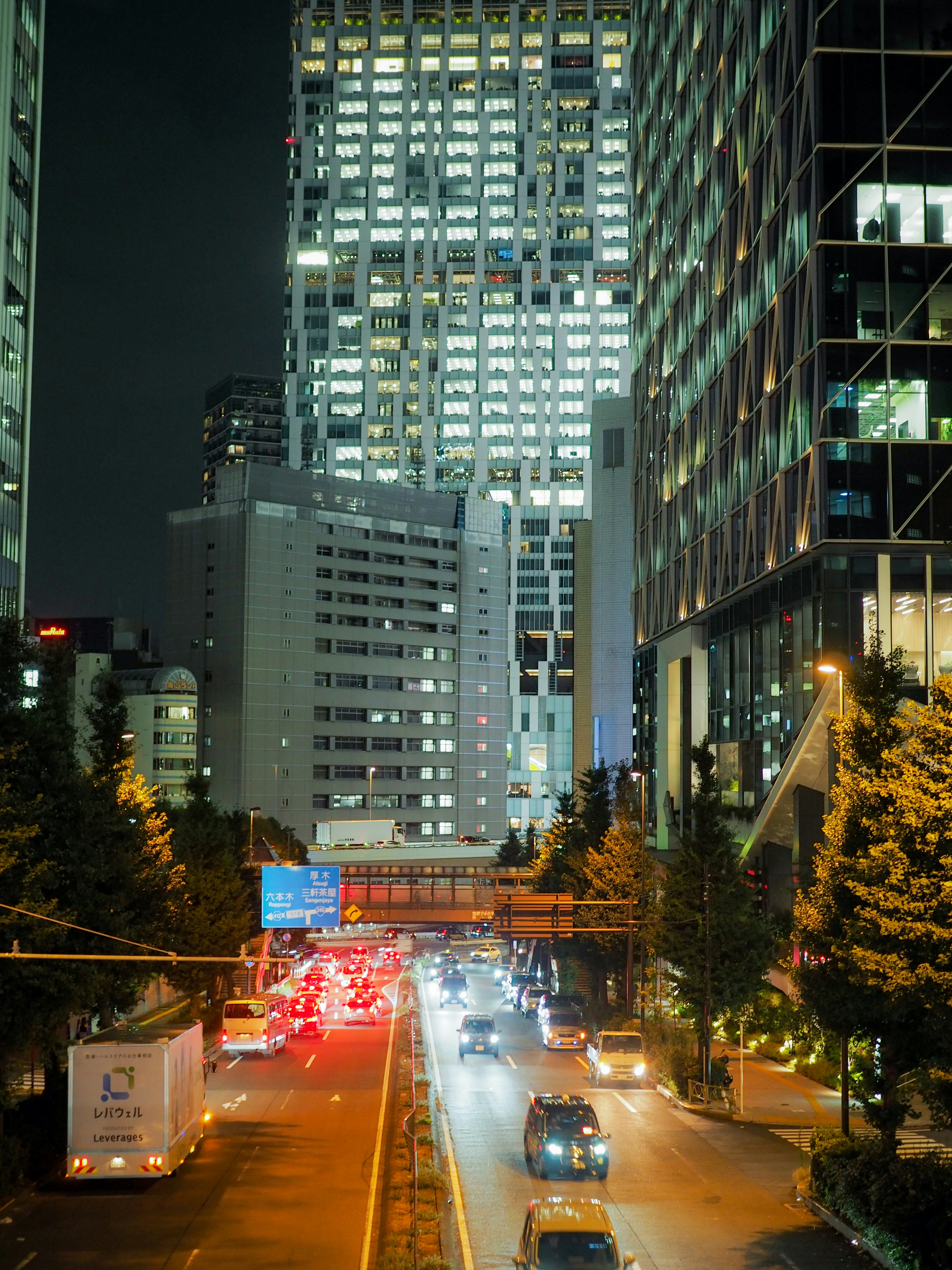 夜の高層ビル街を走る車の光跡