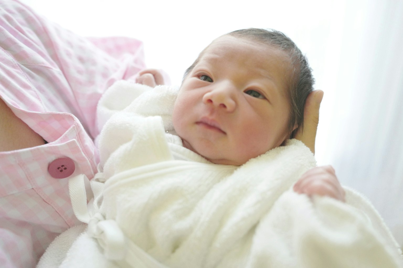 Woman holding a newborn wrapped in a white blanket