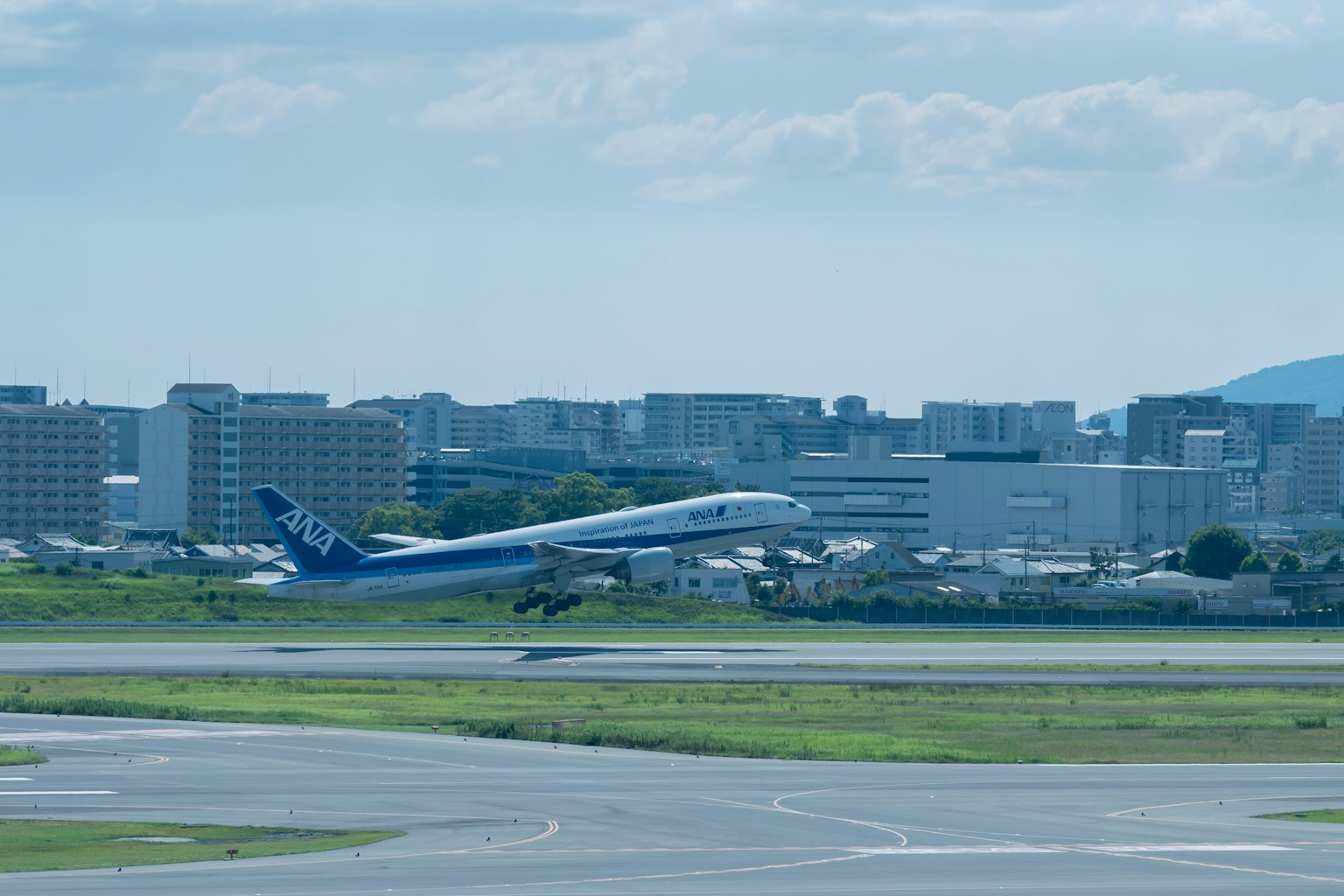 Flugzeug, das von der Landebahn abhebt, mit einer Stadtlandschaft unter blauem Himmel
