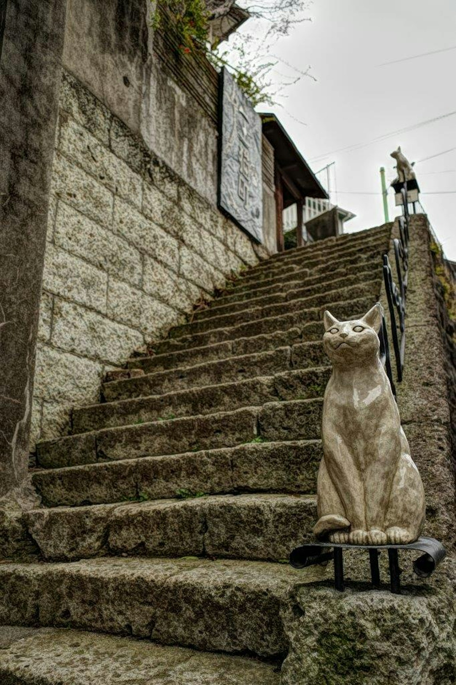 Patung kucing duduk di samping tangga batu