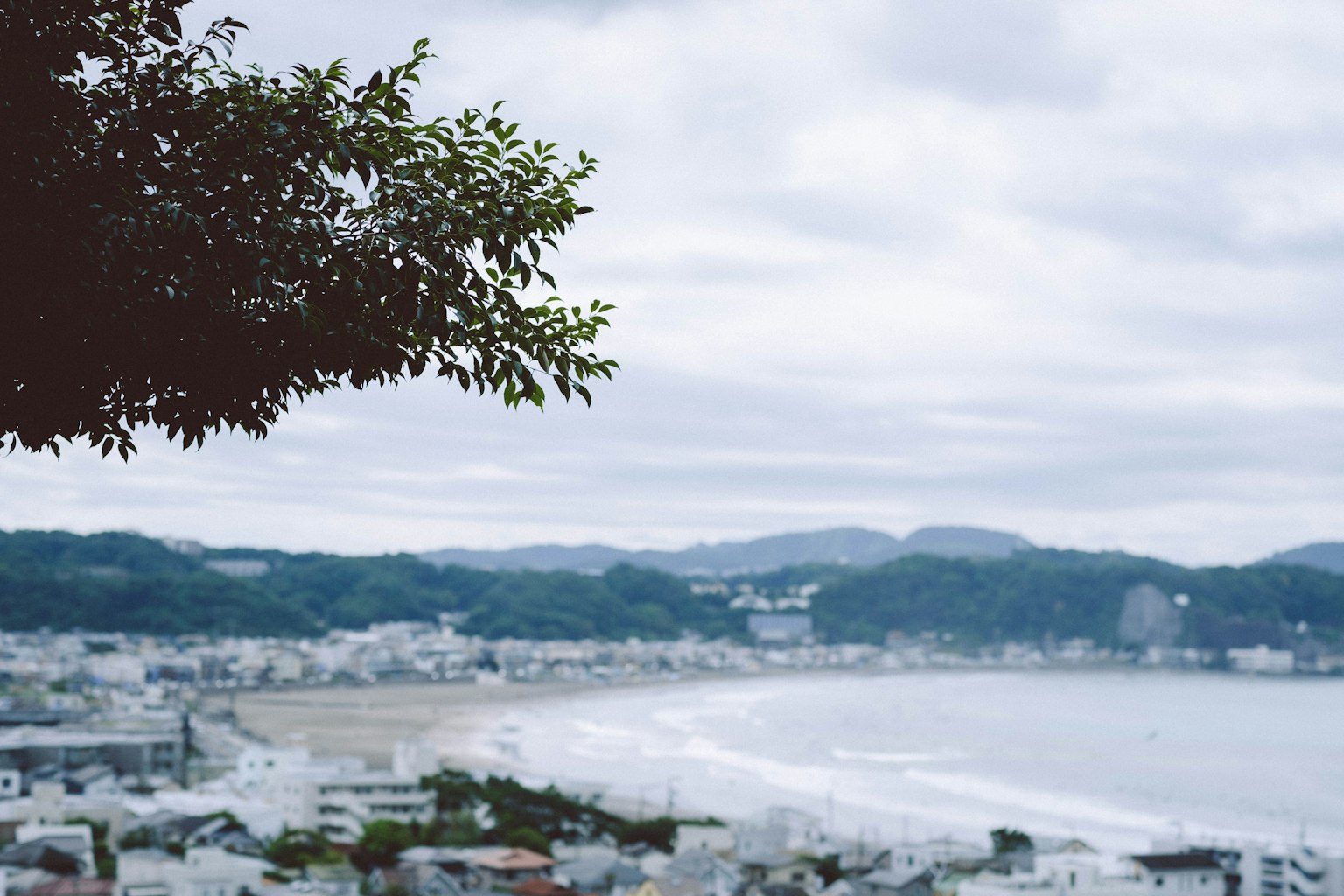 海岸城市景觀，背景為多雲的天空和遠處的山