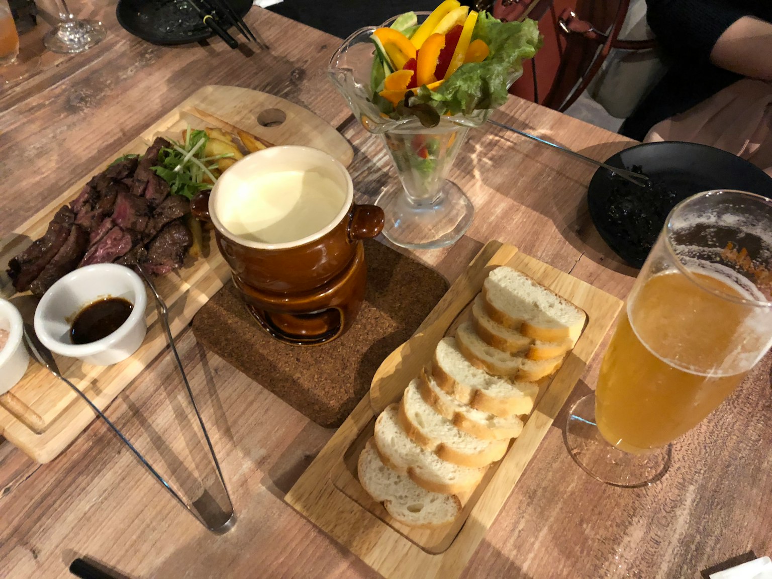 Ein Tisch mit köstlichen Gerichten und Getränken einschließlich Steak, Brot, Salat, Bier und Sauce