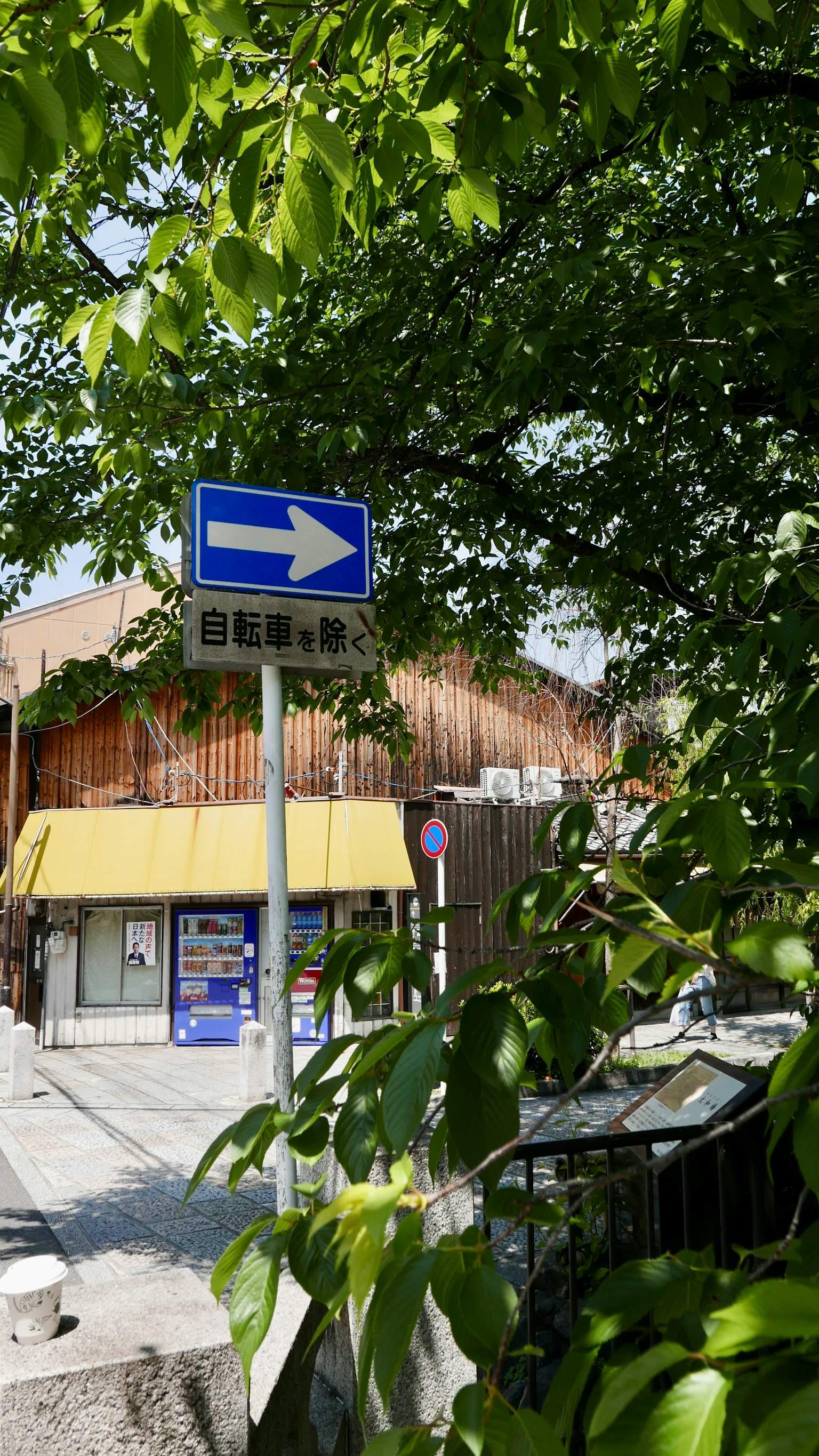 Street corner view featuring a blue directional sign