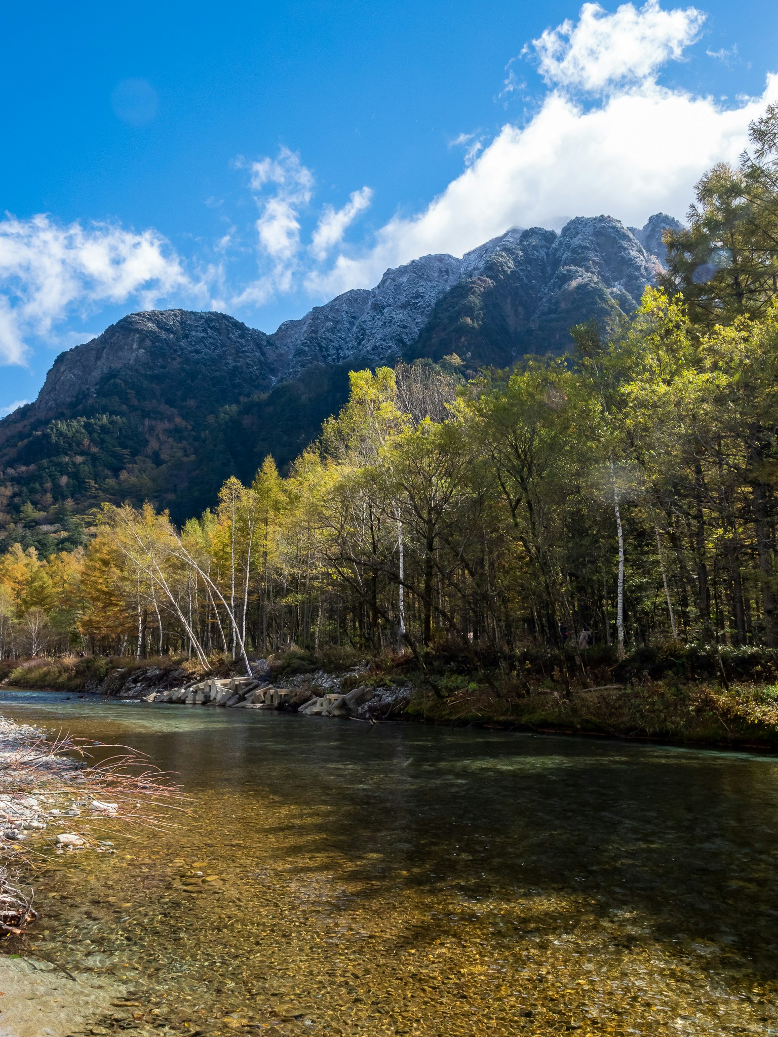 Scenic view of mountains with clear river and autumn foliage