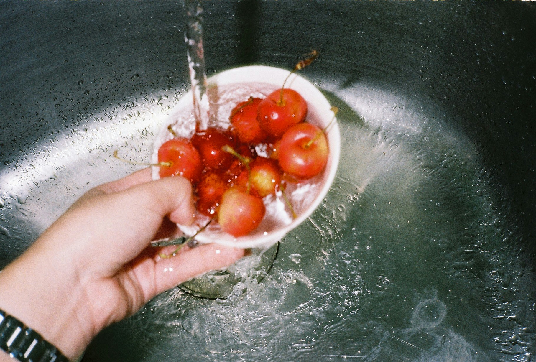手のひらにのせたトマトと水しぶきのあるボウル