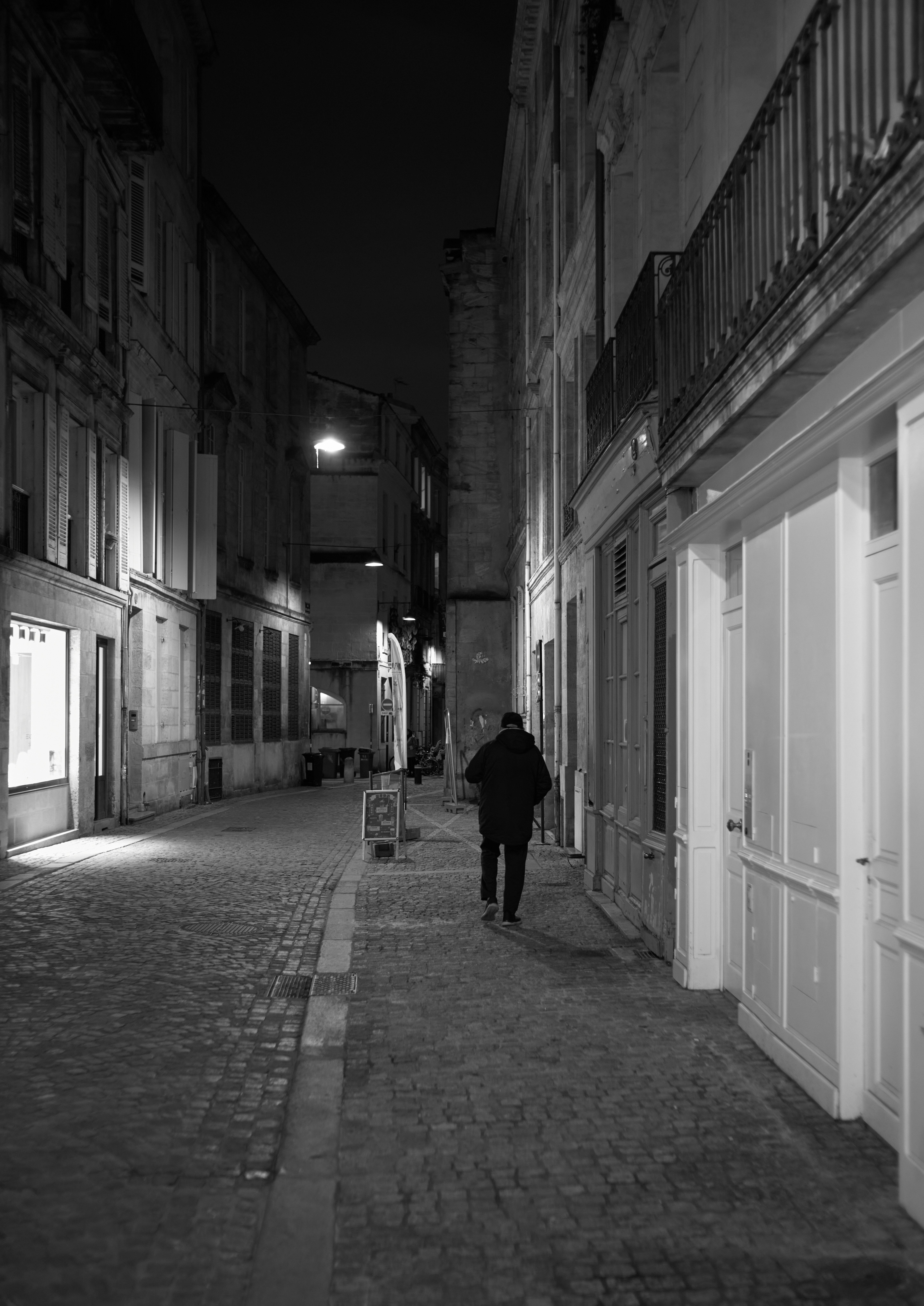 夜の細い路地を歩くひとりの人物のシルエット
