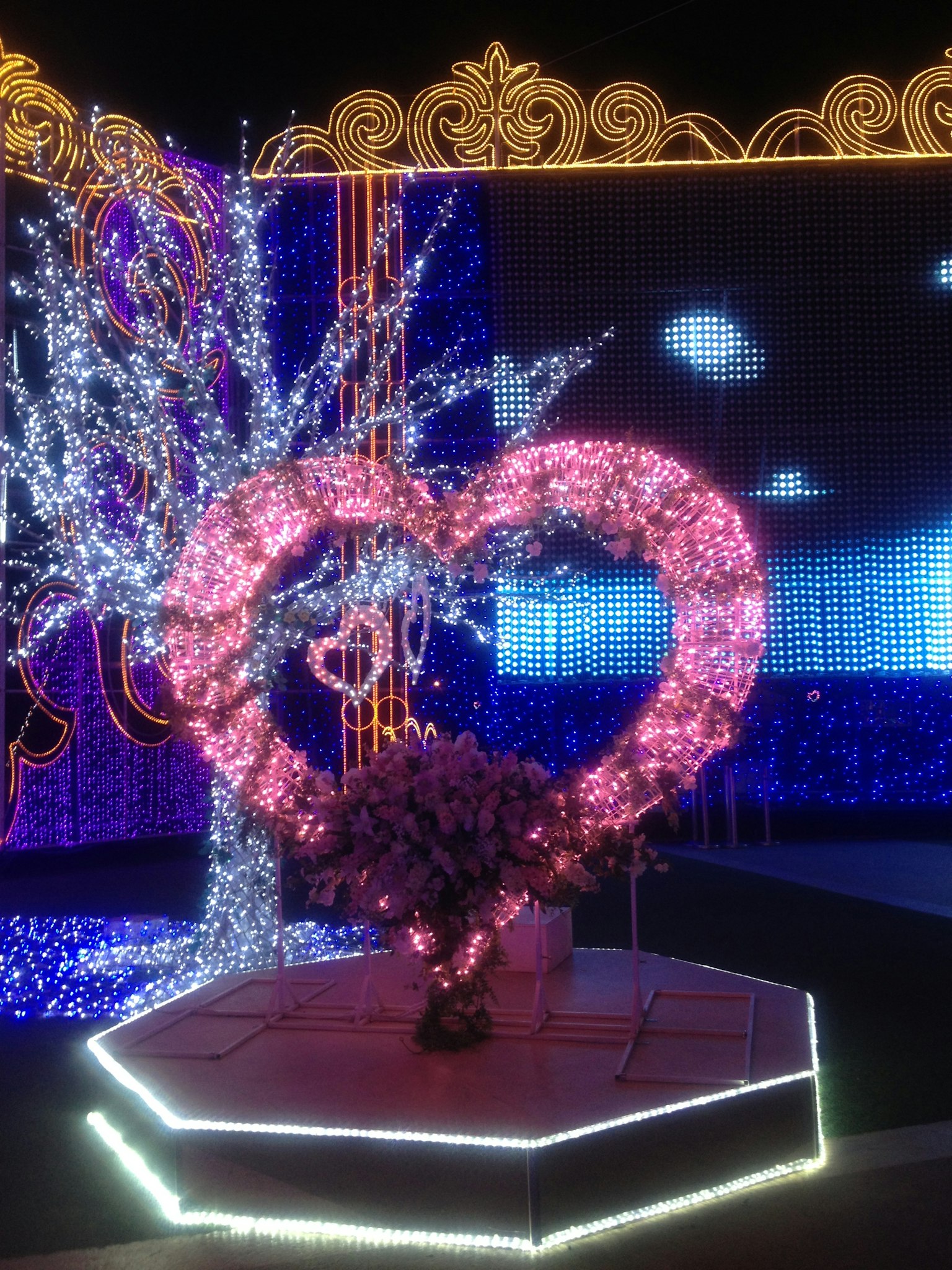 A heart-shaped art installation adorned with colorful lights against a whimsical backdrop