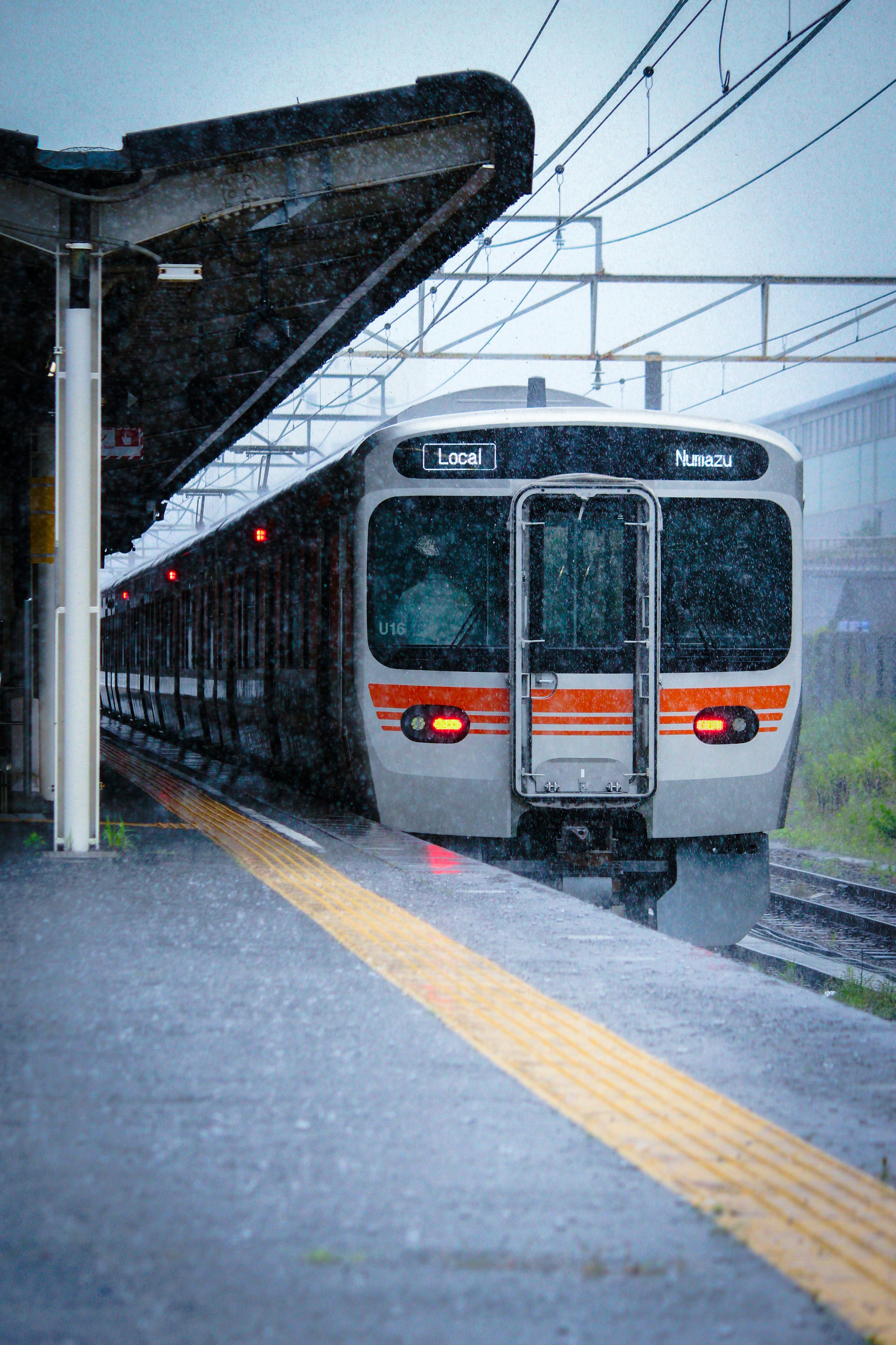 大雨の駅で停車する電車