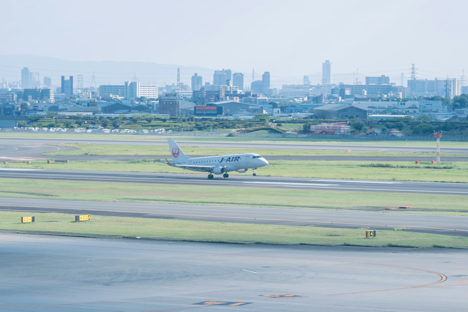 Flugzeug rollt auf der Landebahn mit Stadtsilhouette im Hintergrund