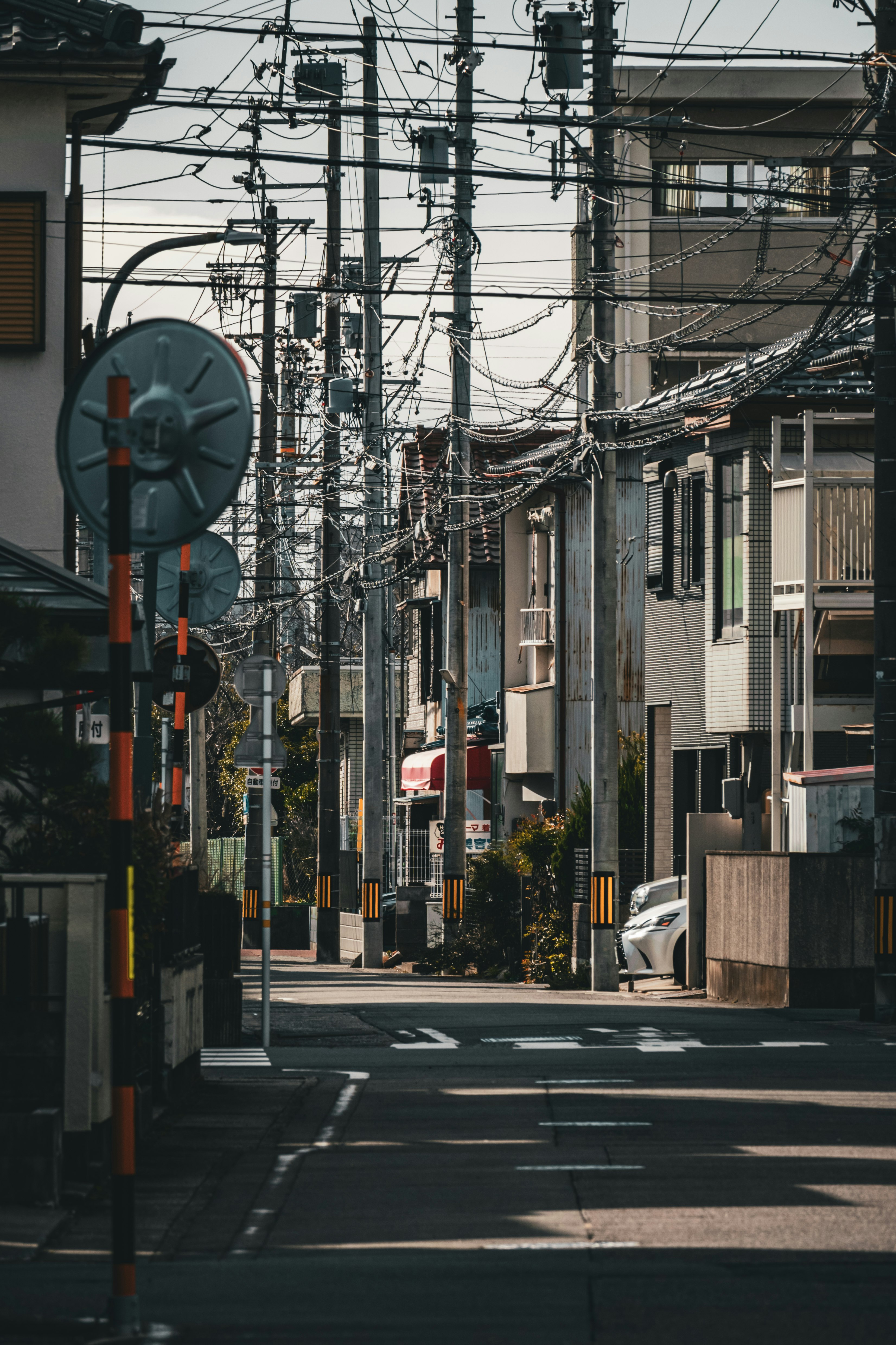 rue étroite de quartier commerçant avec poteaux électriques et câbles aériens
