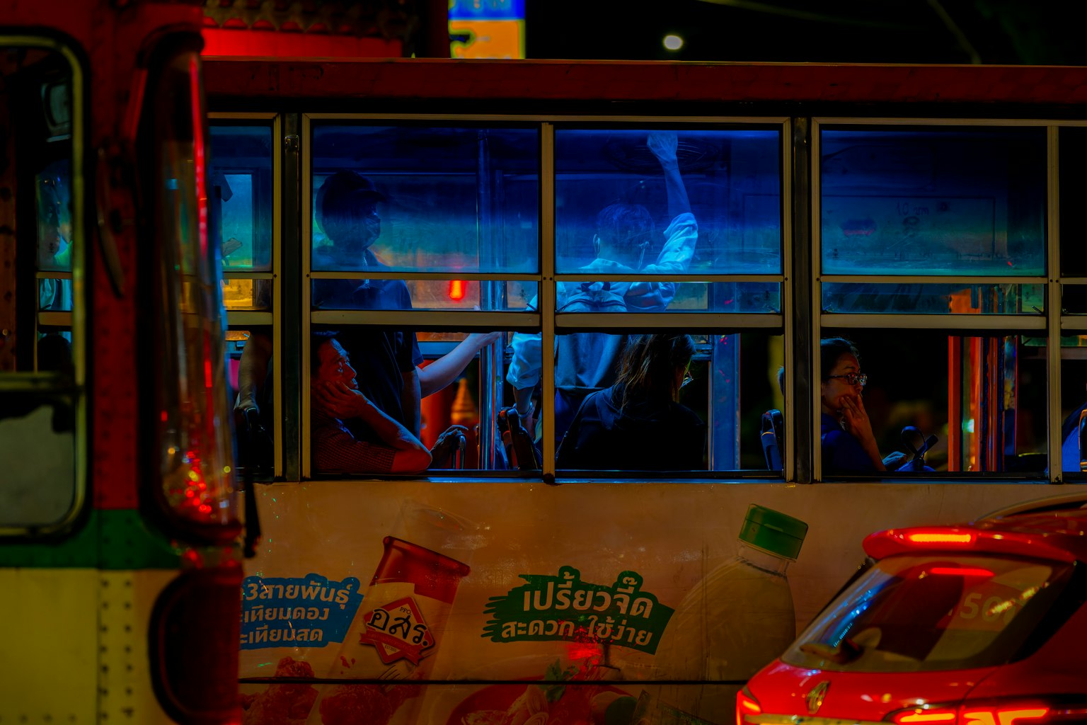 夜晚被藍光照亮的公車內坐著的人們