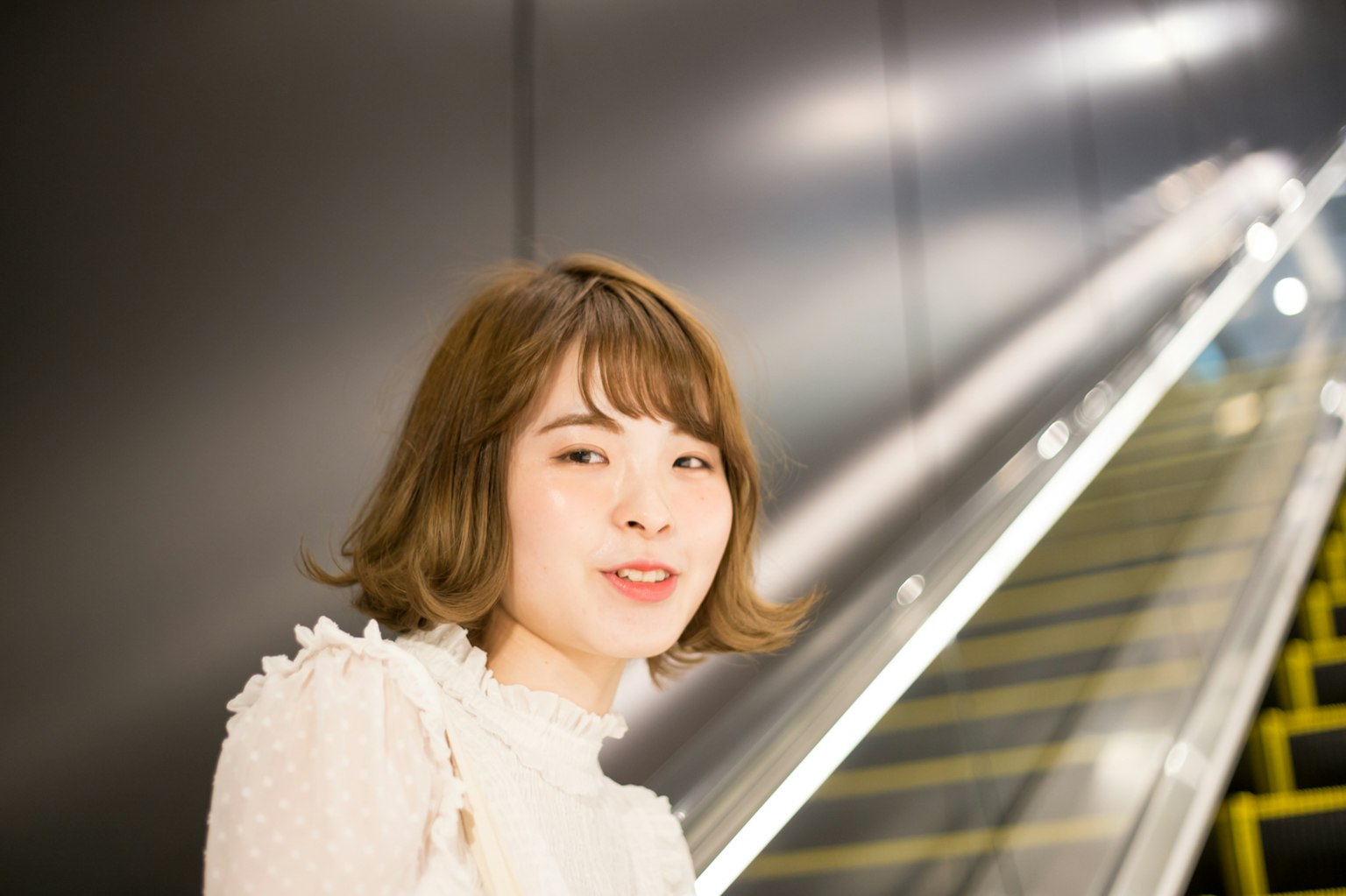 Retrato de una mujer sonriendo cerca de una escalera mecánica