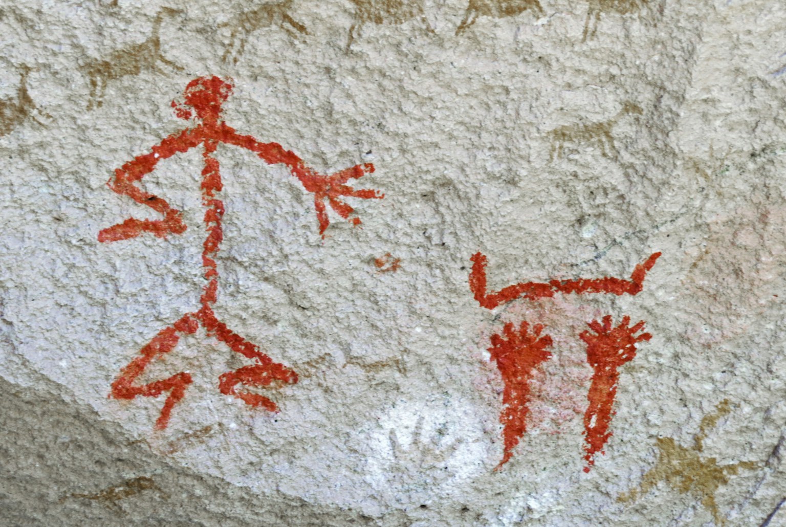 Ancient cave painting featuring red stick figure and handprints