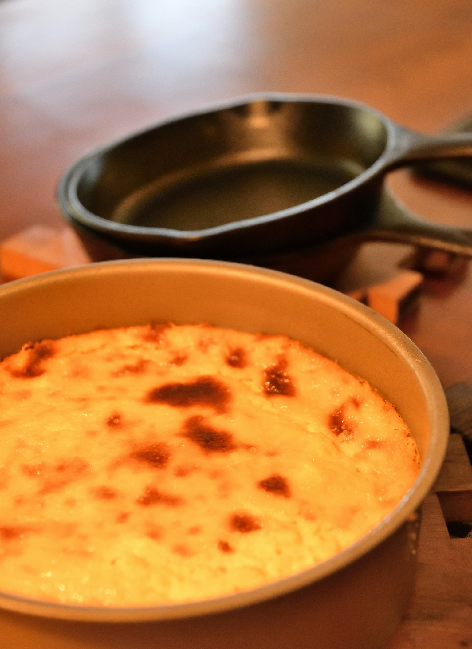 Creamy souffle with browned top next to a cast iron skillet