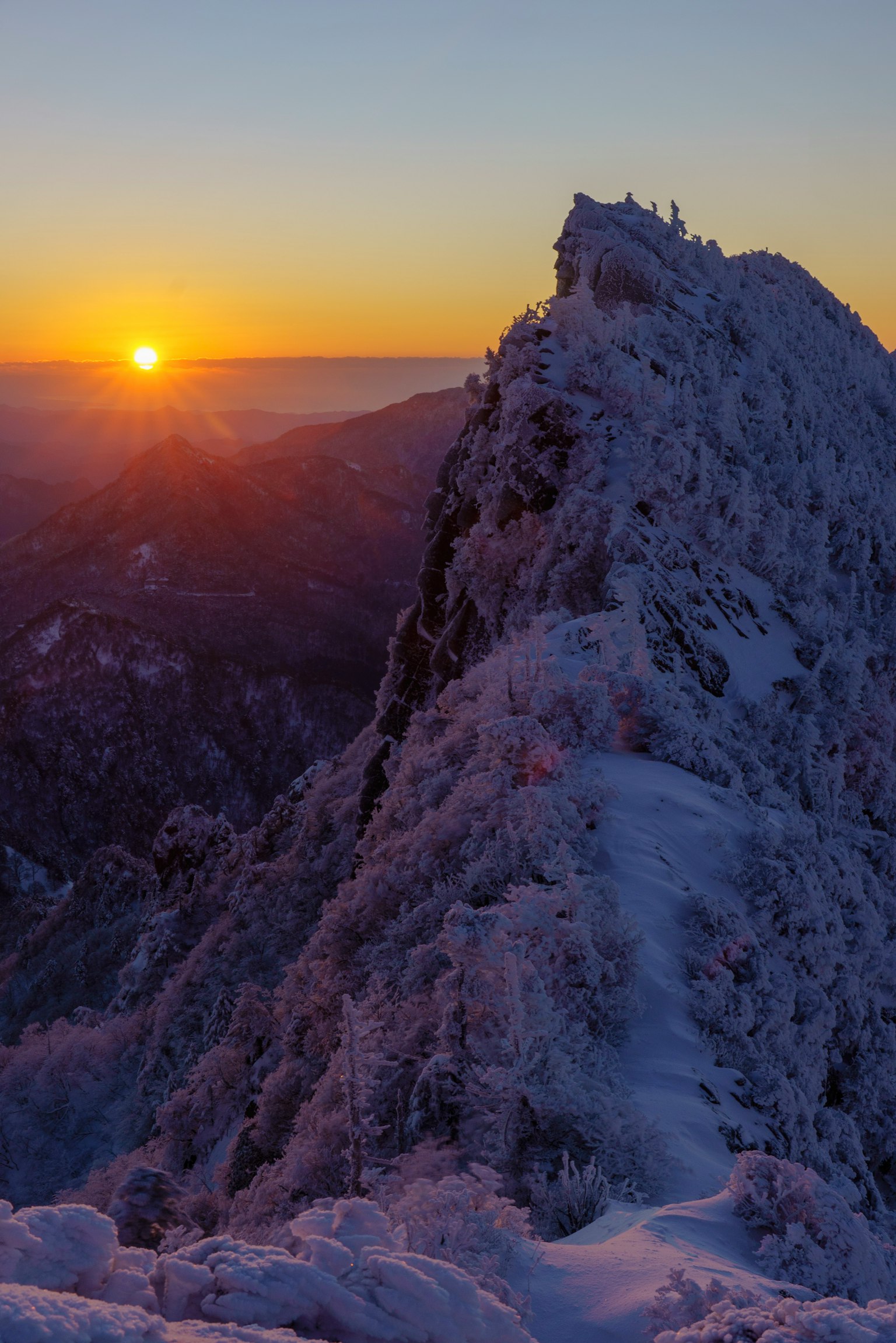Cima de montaña nevada con atardecer