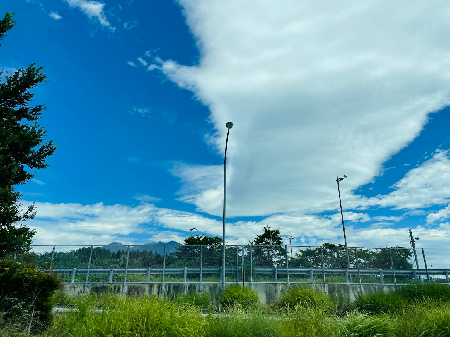 ทิวทัศน์ที่สวยงามพร้อมท้องฟ้าสีฟ้าและเมฆสีขาวหญ้าสีเขียวและรั้วมองเห็นได้
