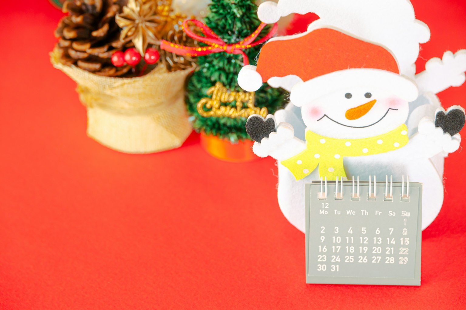 Weihnachtsdekorationen mit einem fröhlichen Schneemann und einem Kalender auf rotem Hintergrund