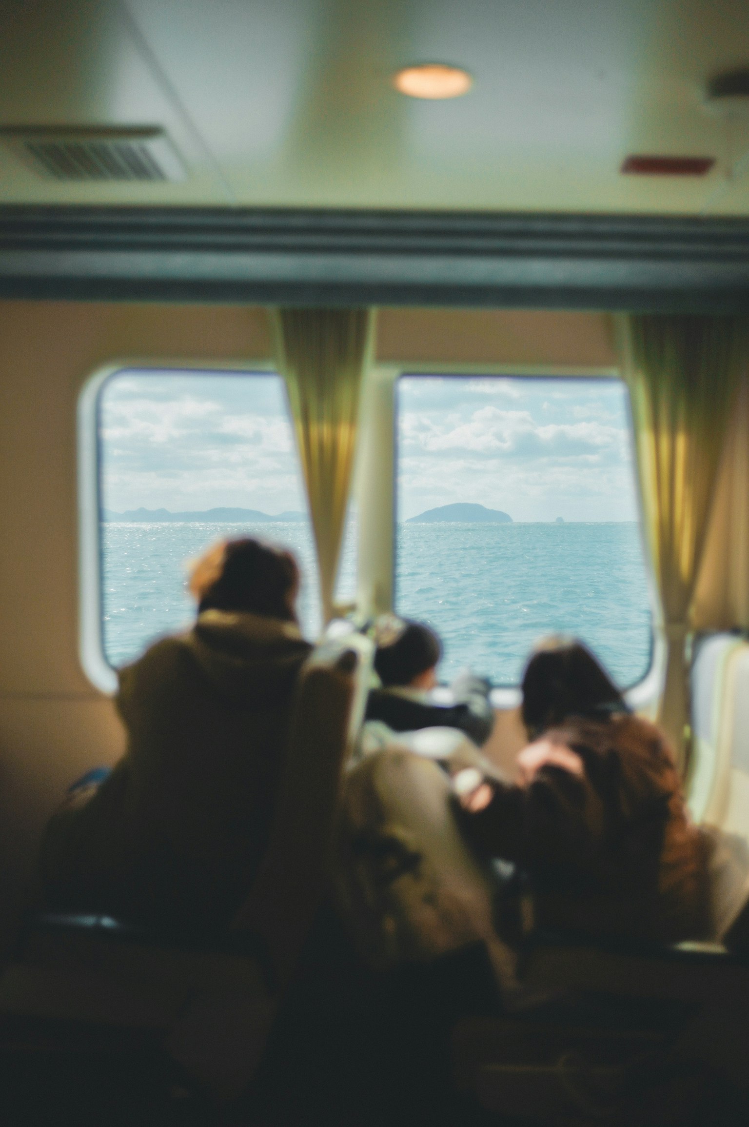 Personnes assises près d'une fenêtre sur un bateau regardant la mer