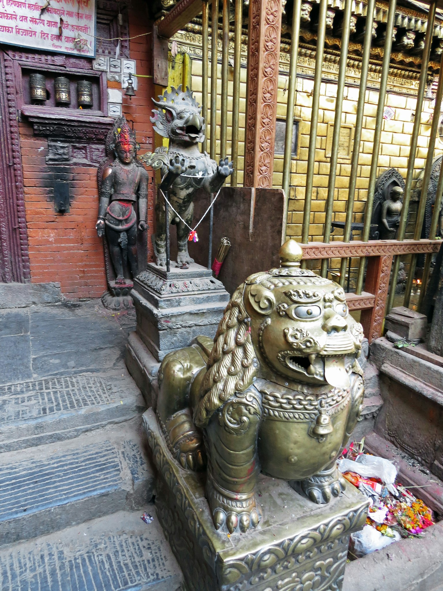 Golden lion statue at the entrance of a temple with another statue in the background