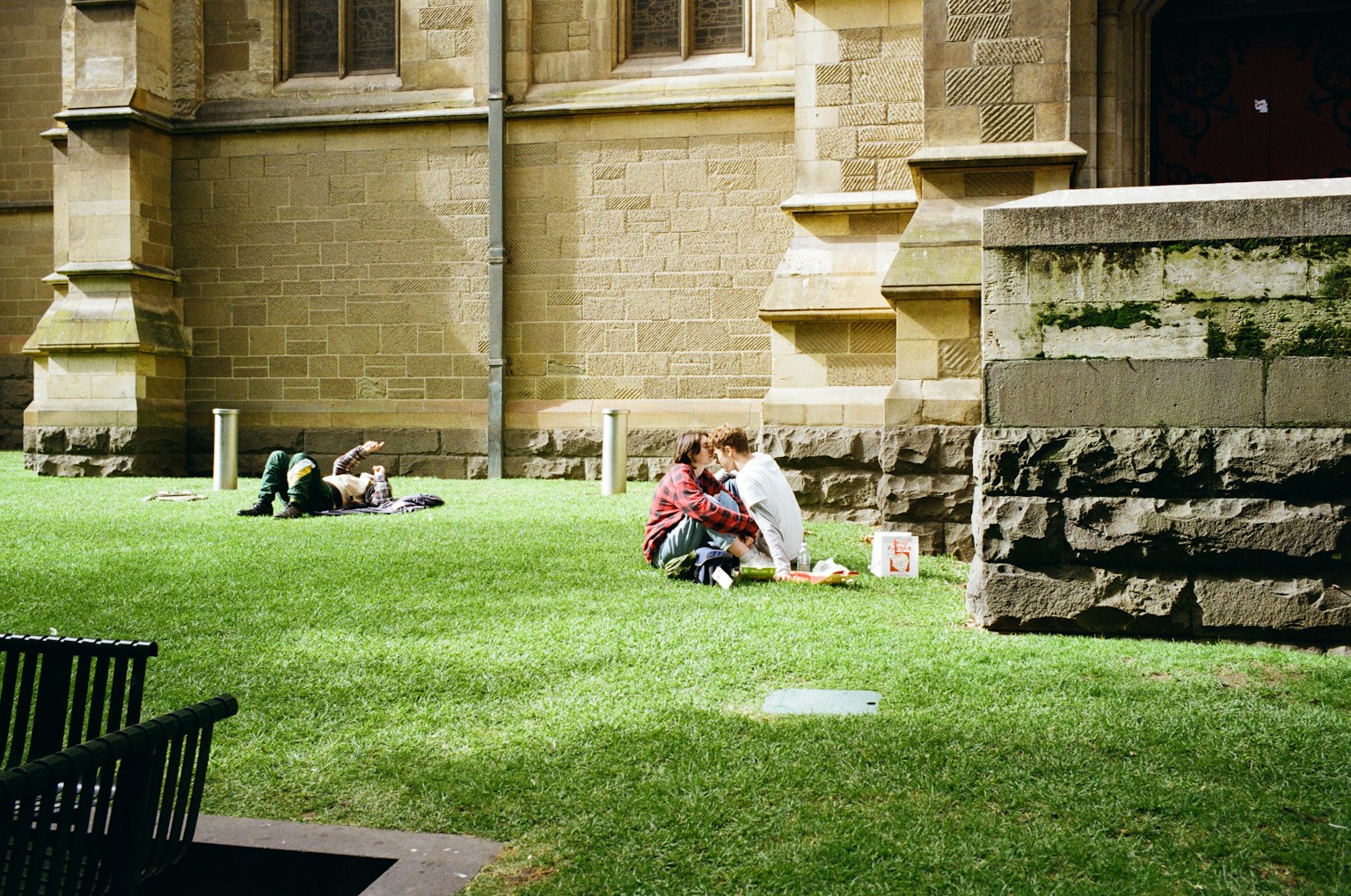 A couple having a picnic on green grass with other people in the background