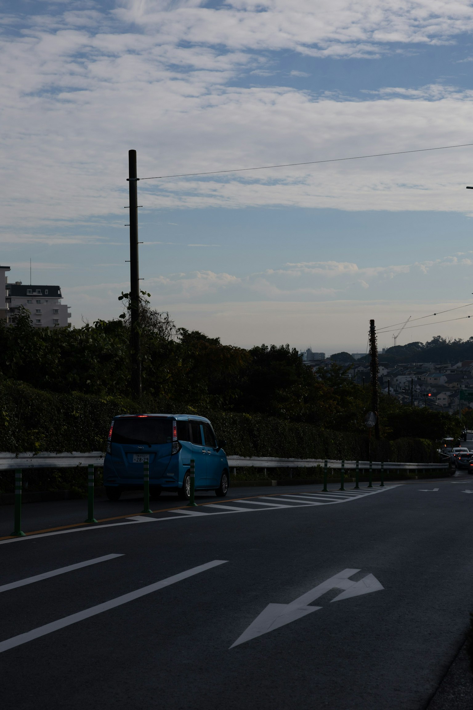 รถยนต์สีน้ำเงินจอดอยู่ข้างถนนท่ามกลางท้องฟ้าที่มีเมฆ