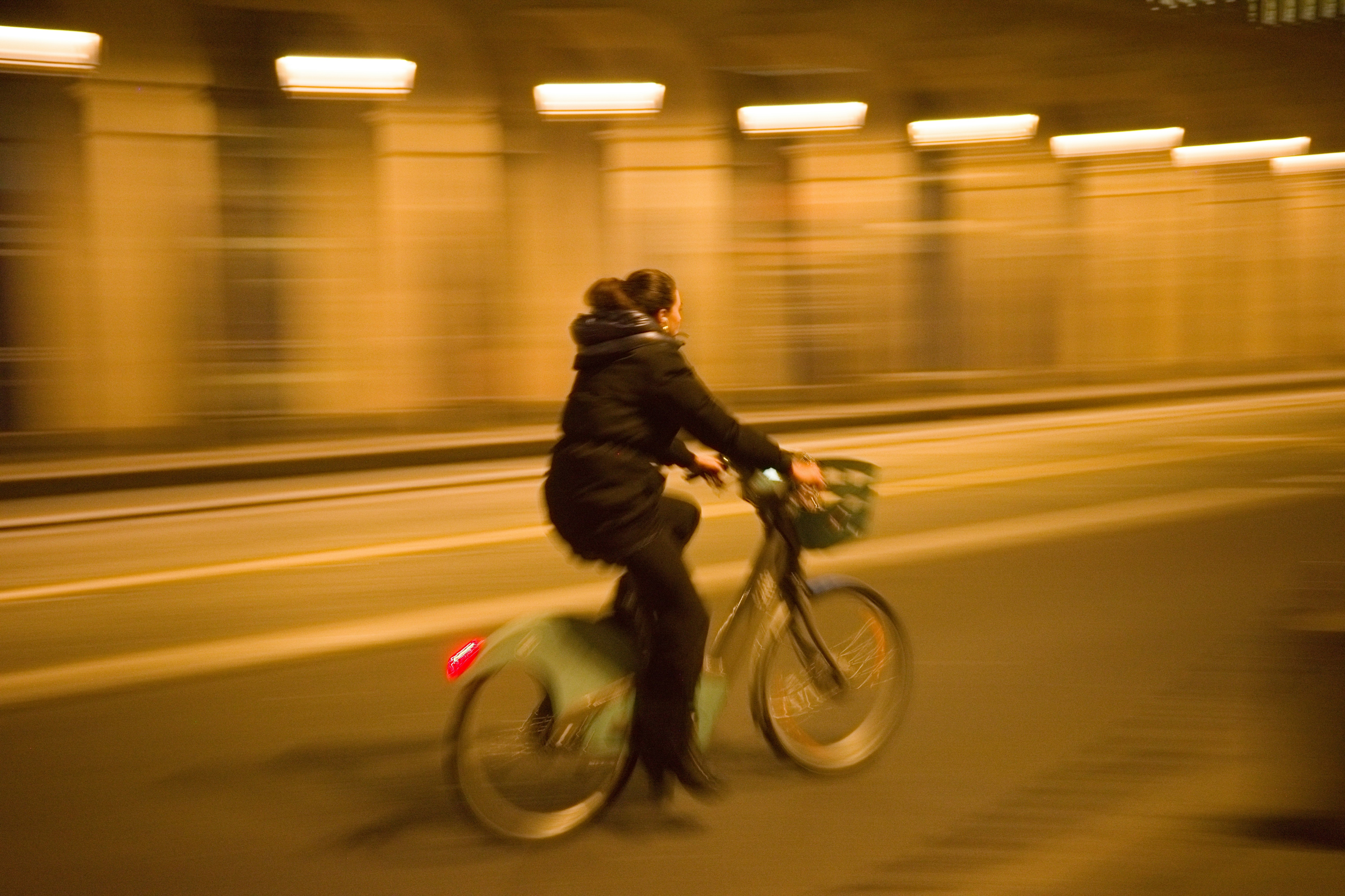 夜の街で自転車に乗る人の流し撮り