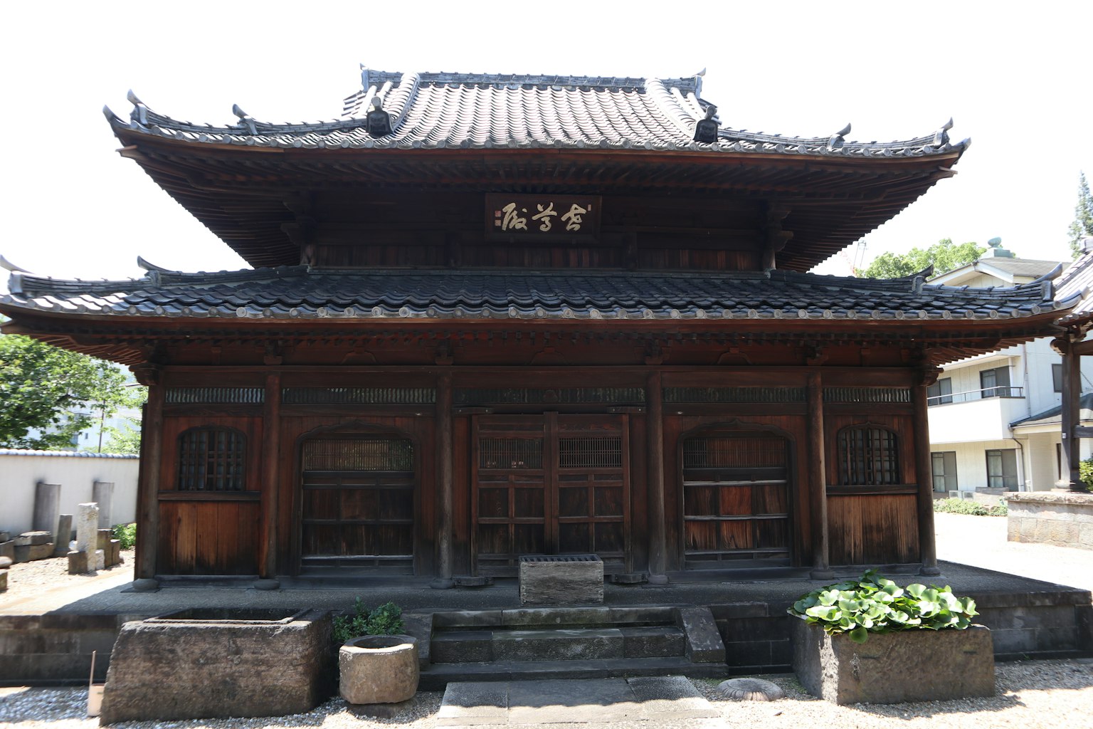 Eksterior bangunan Jepang tradisional dengan struktur kayu dekorasi atap yang rumit dan tanaman taman yang terlihat