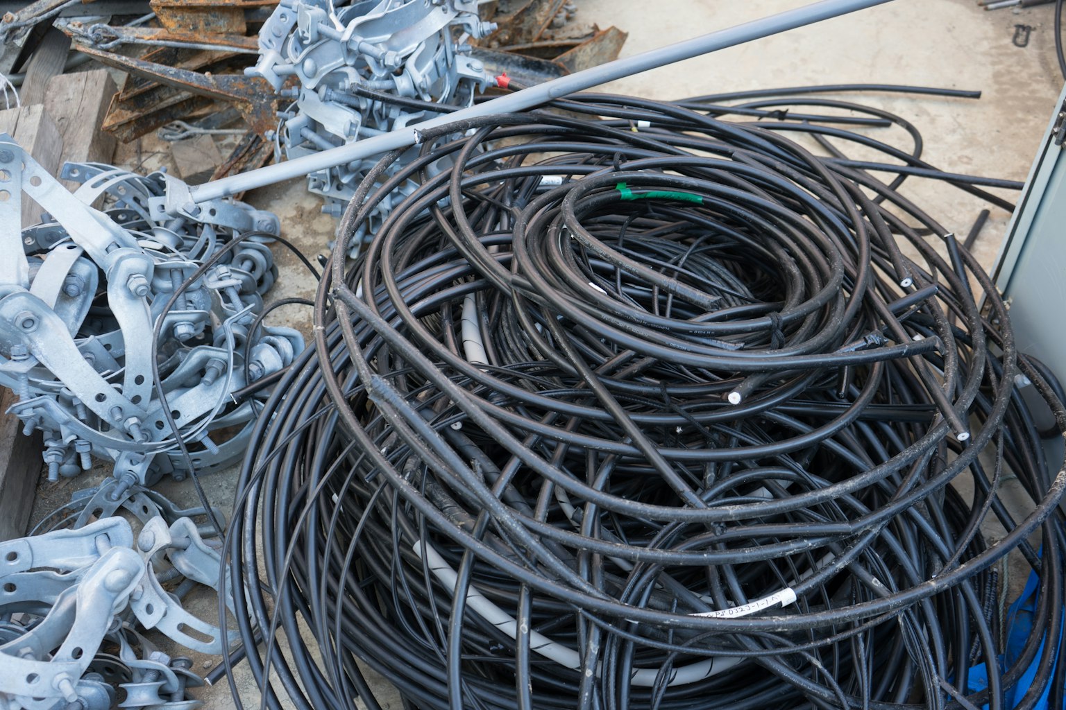 Una foto di cavi neri attorcigliati e rottami metallici in un'area di stoccaggio