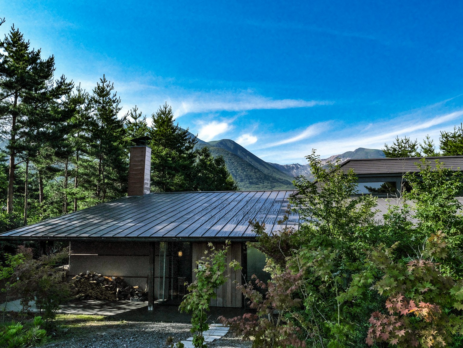 Casa moderna rodeada de exuberante vegetación con montañas y cielo azul de fondo