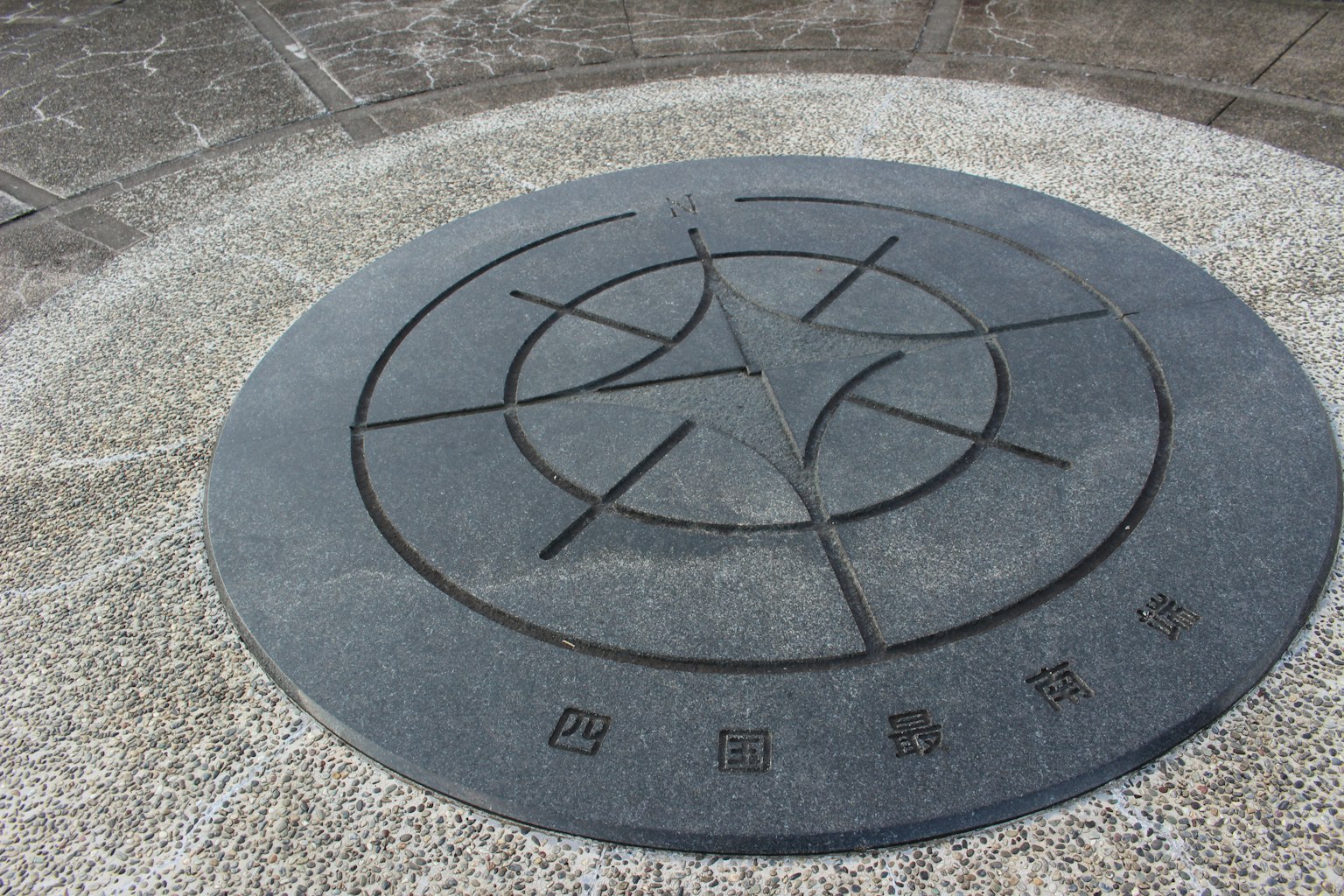 Monumento circolare in pietra con simboli e testo incisi