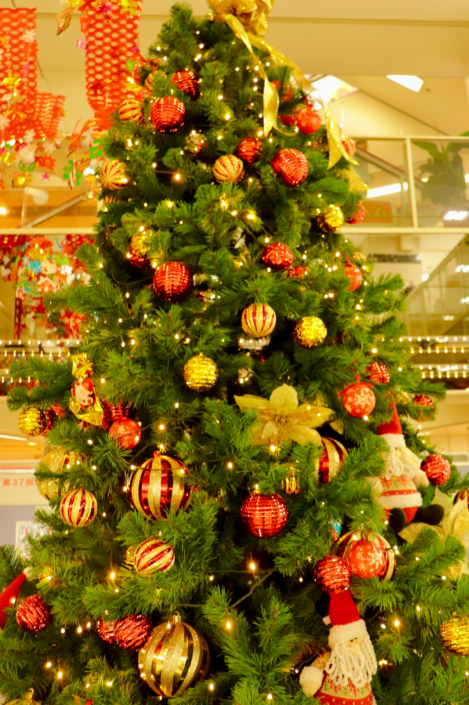 Albero di Natale decorato con ornamenti rossi e dorati e luci calde
