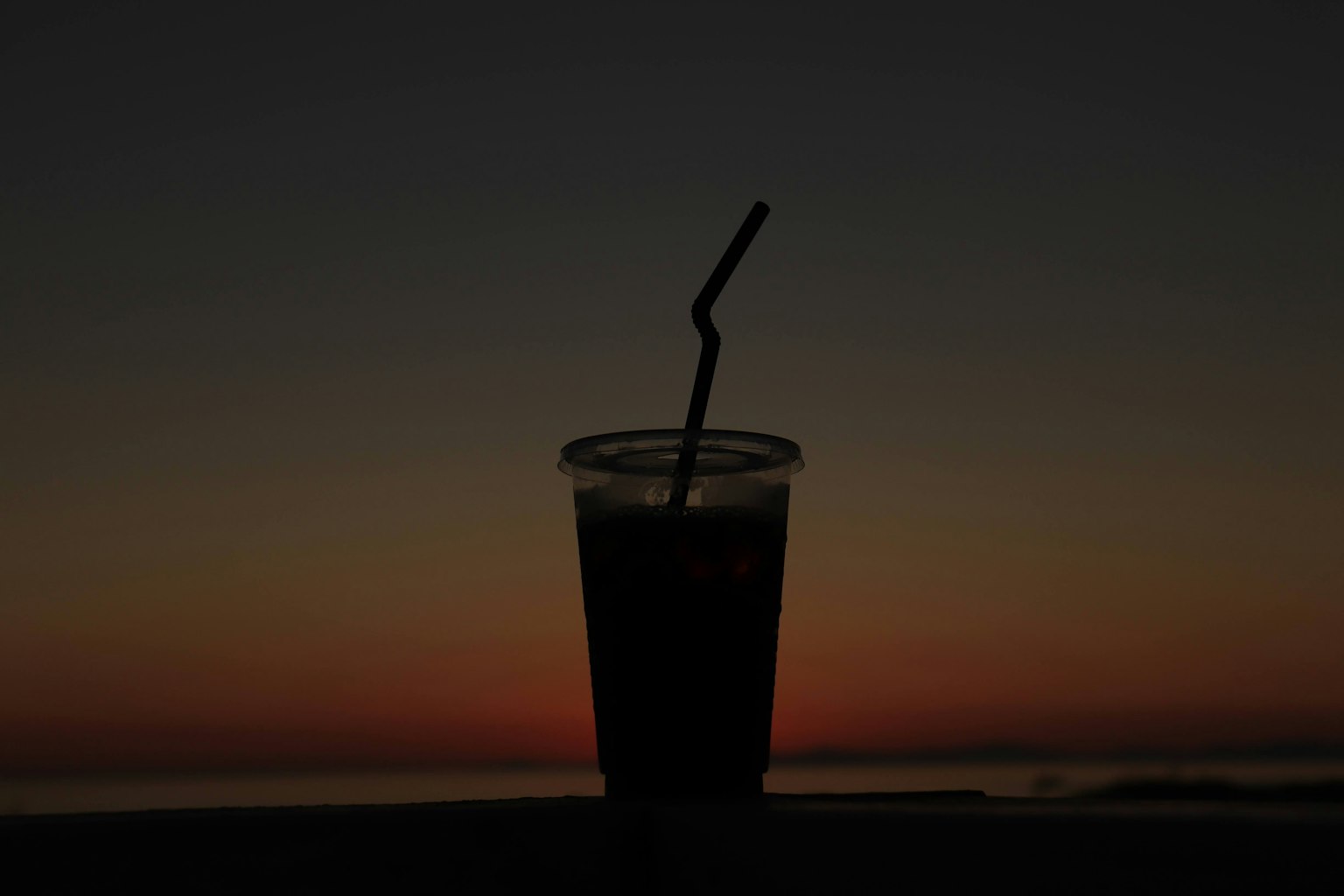 Silhouette eines Getränks mit einem Strohhalm bei Sonnenuntergang