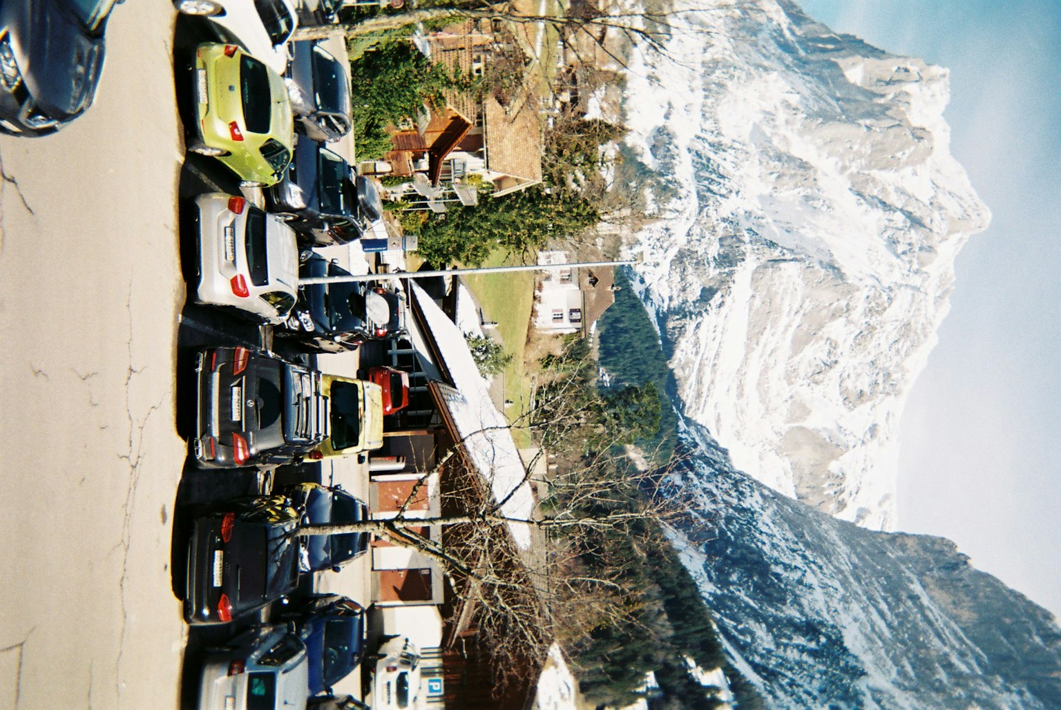 Auto parcheggiate in un parcheggio con montagne innevate sullo sfondo