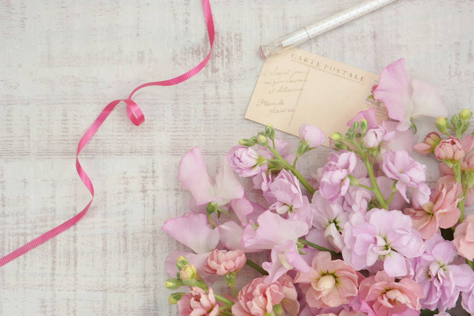 Composizione di fiori rosa con un nastro su un tavolo di legno