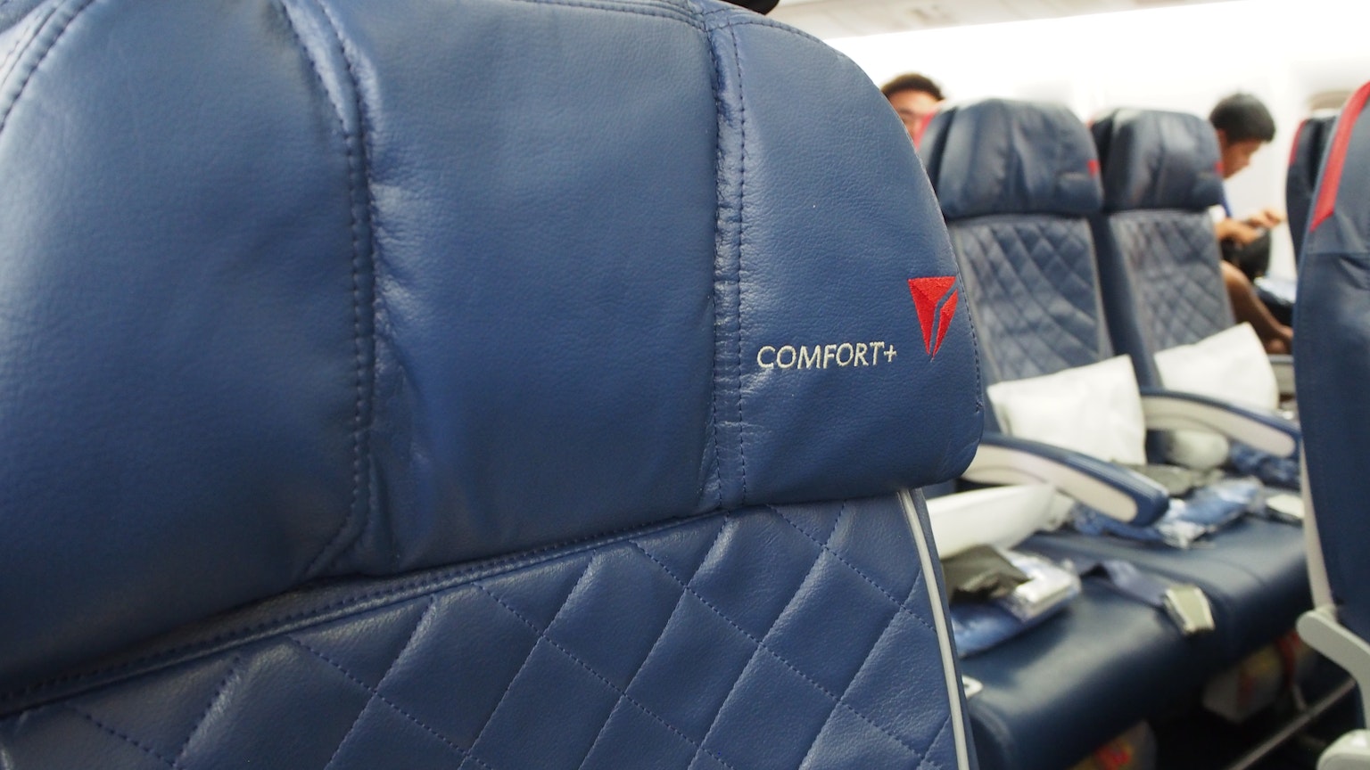 Tampilan dekat kursi pesawat kulit biru dengan logo 'COMPACT' terlihat