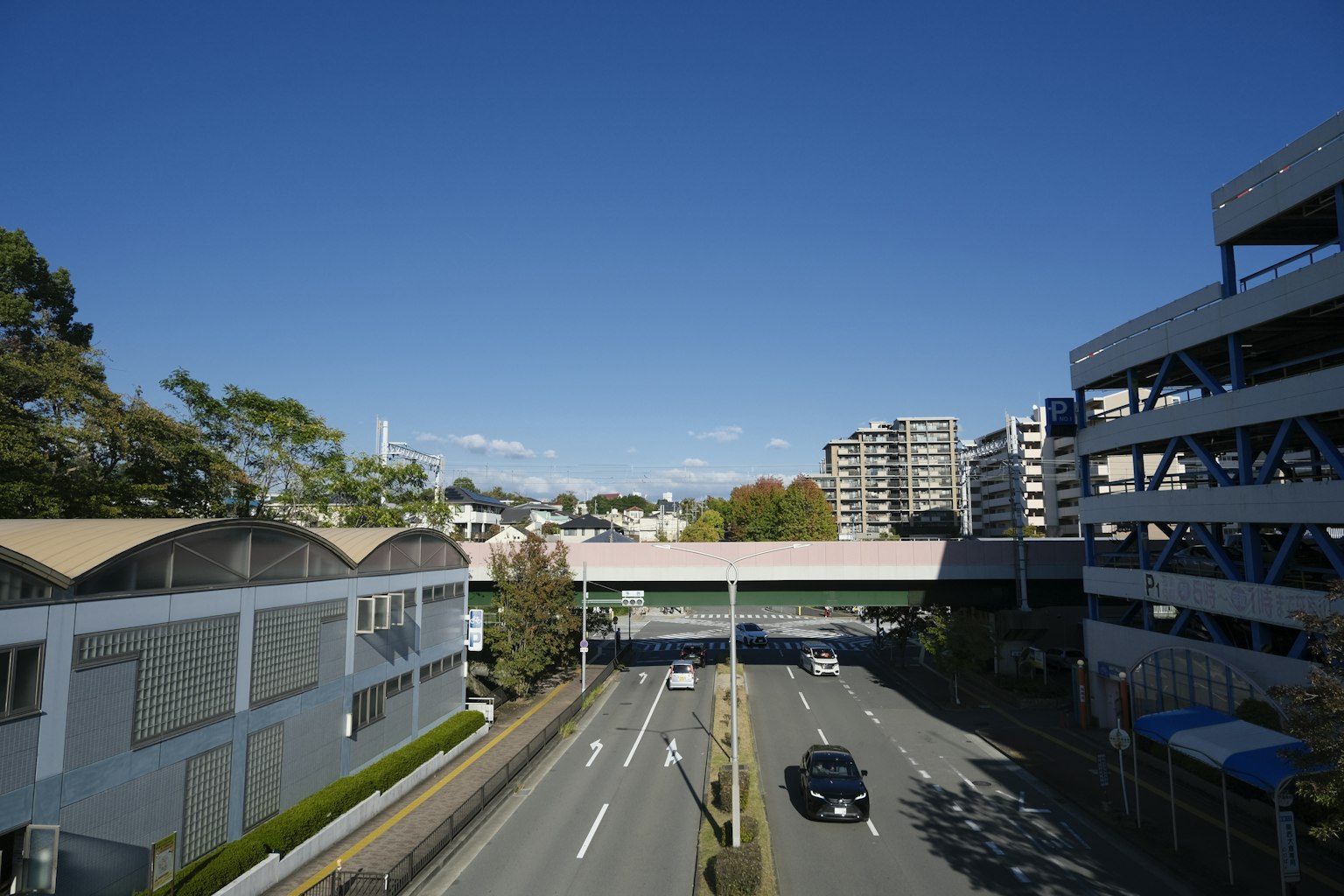 Paysage urbain sous un ciel bleu clair avec une route et un parking