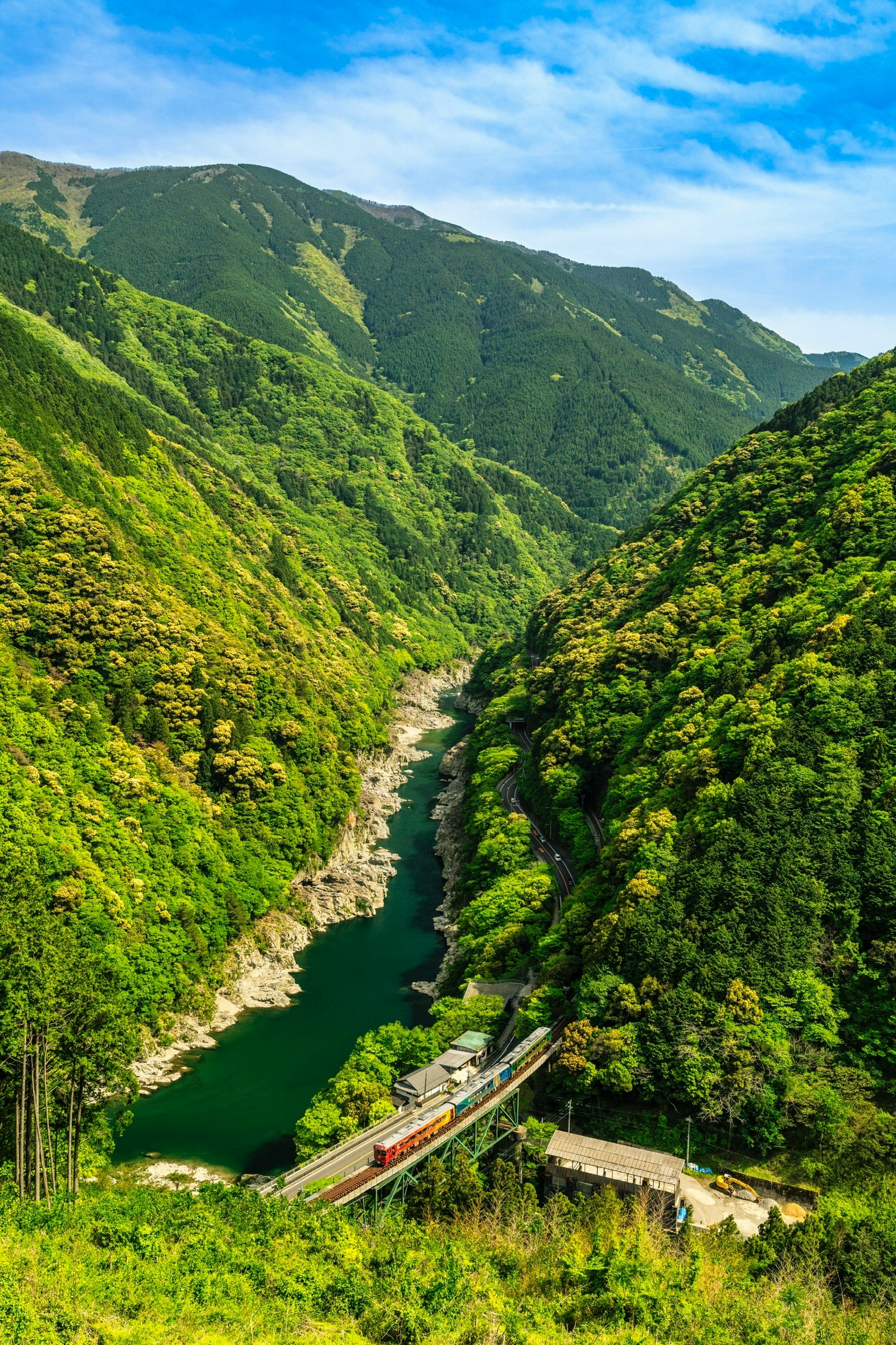 Scenic view of a river surrounded by lush green mountains and a railway