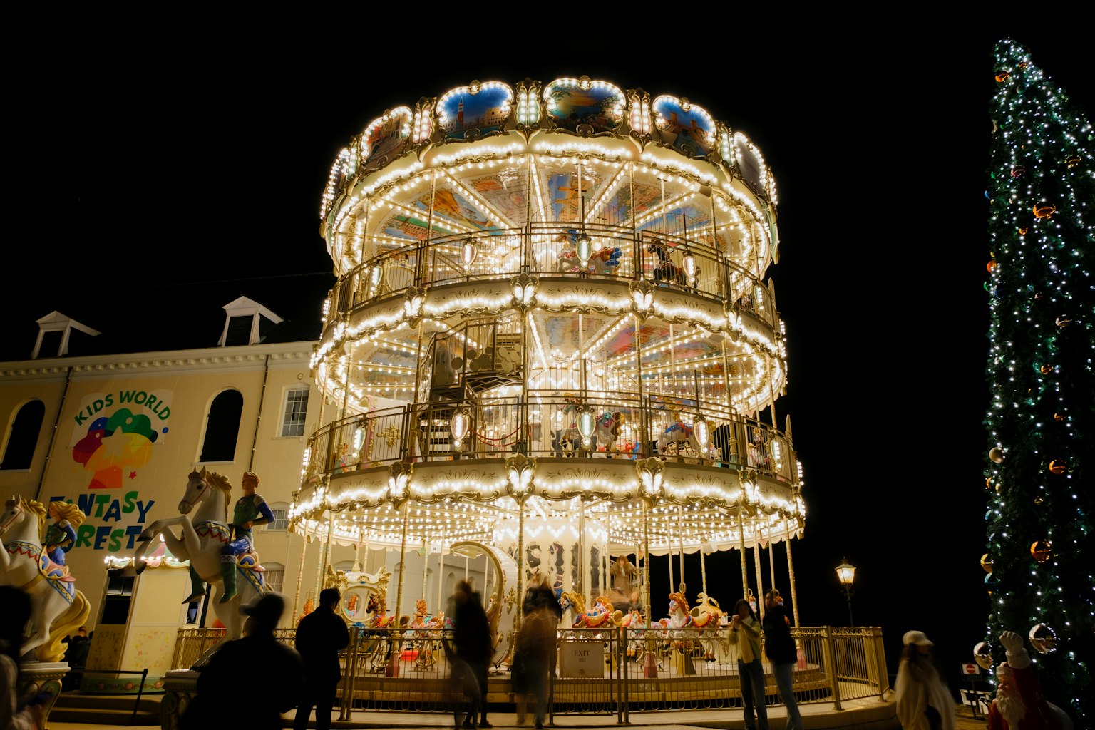 Immagine di un carosello a tre piani illuminato di notte in un parco divertimenti