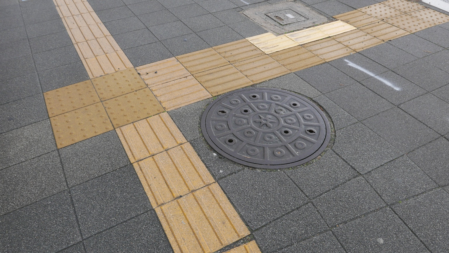 人行道的一部分，展示了铺路砖和一个井盖
