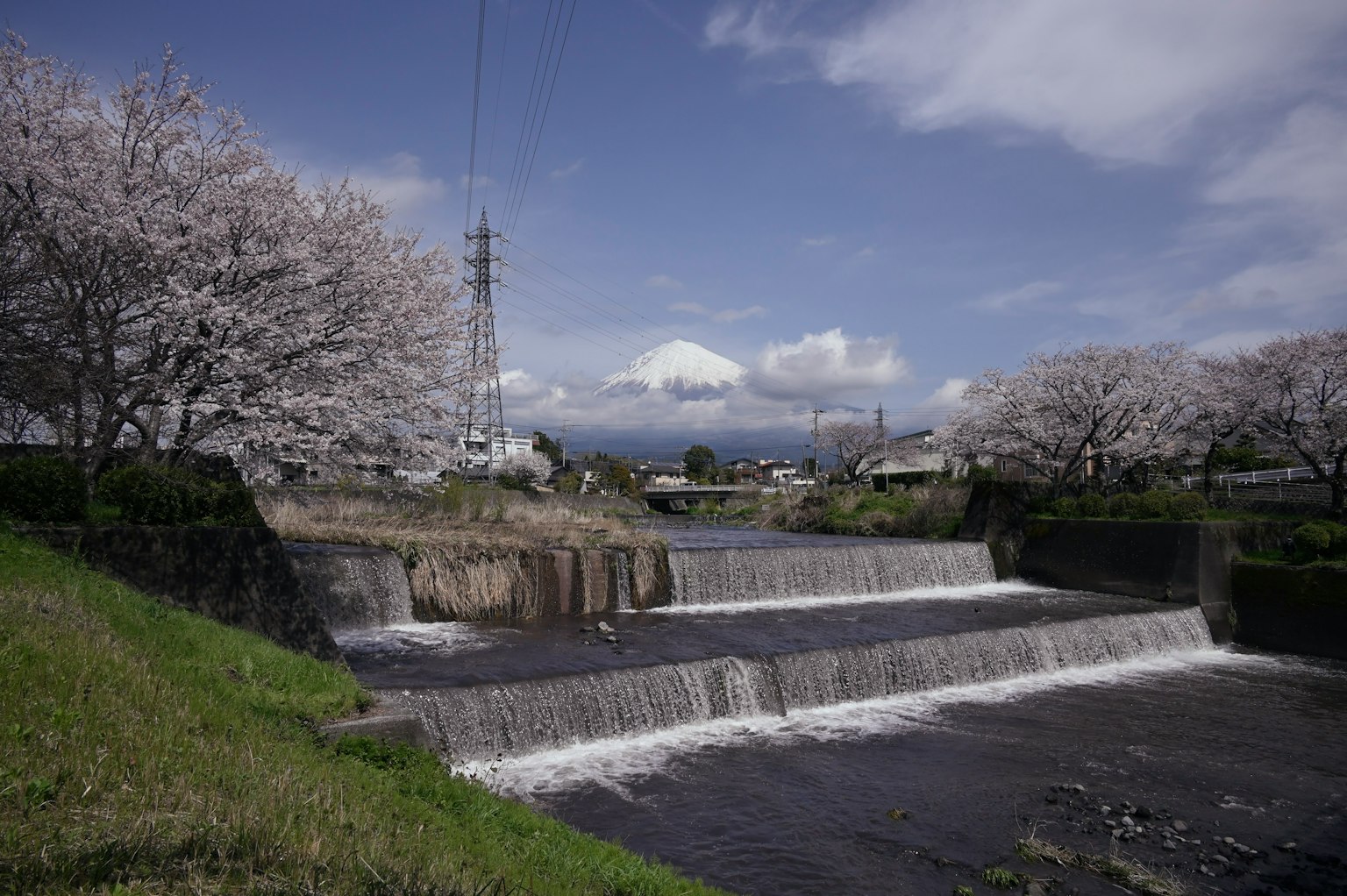 Vista escénica de un río y una cascada rodeados de cerezos en flor