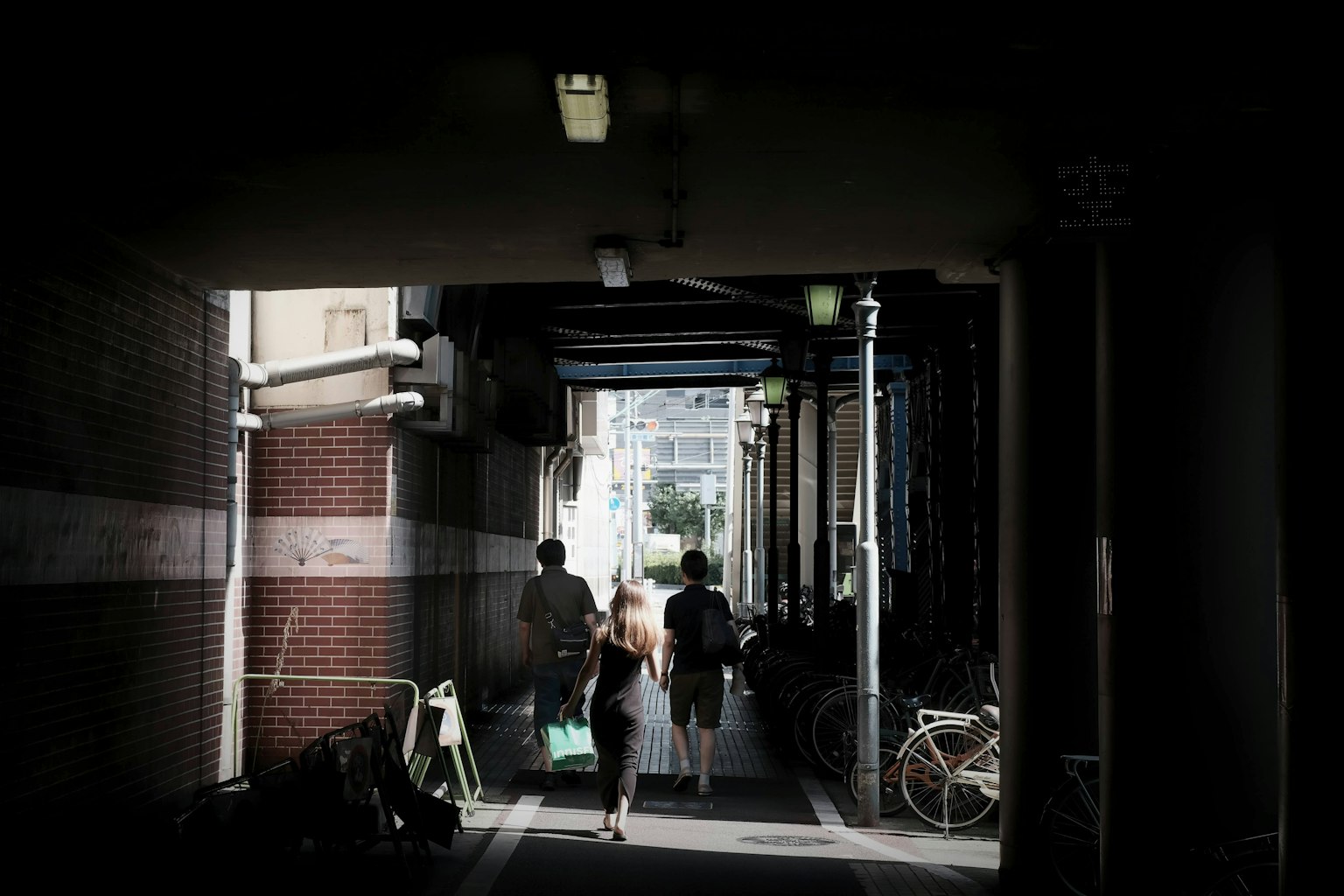 Des personnes marchant dans un passage sombre avec des vélos alignés