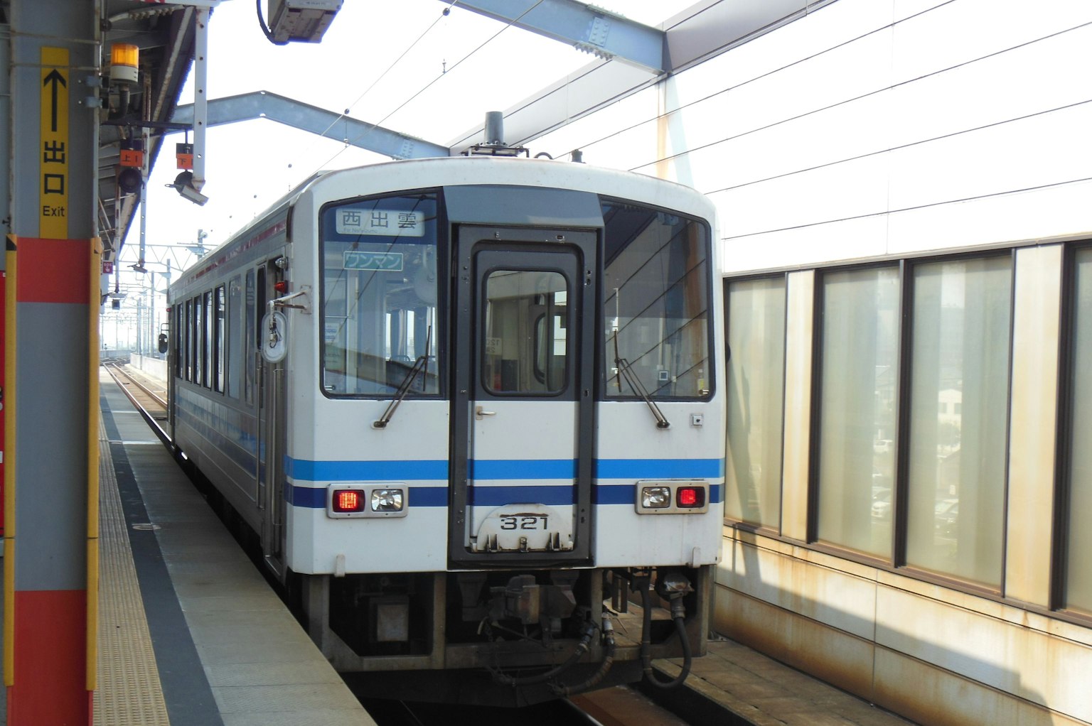 Blauer und weißer Zug hält an einem Bahnhof