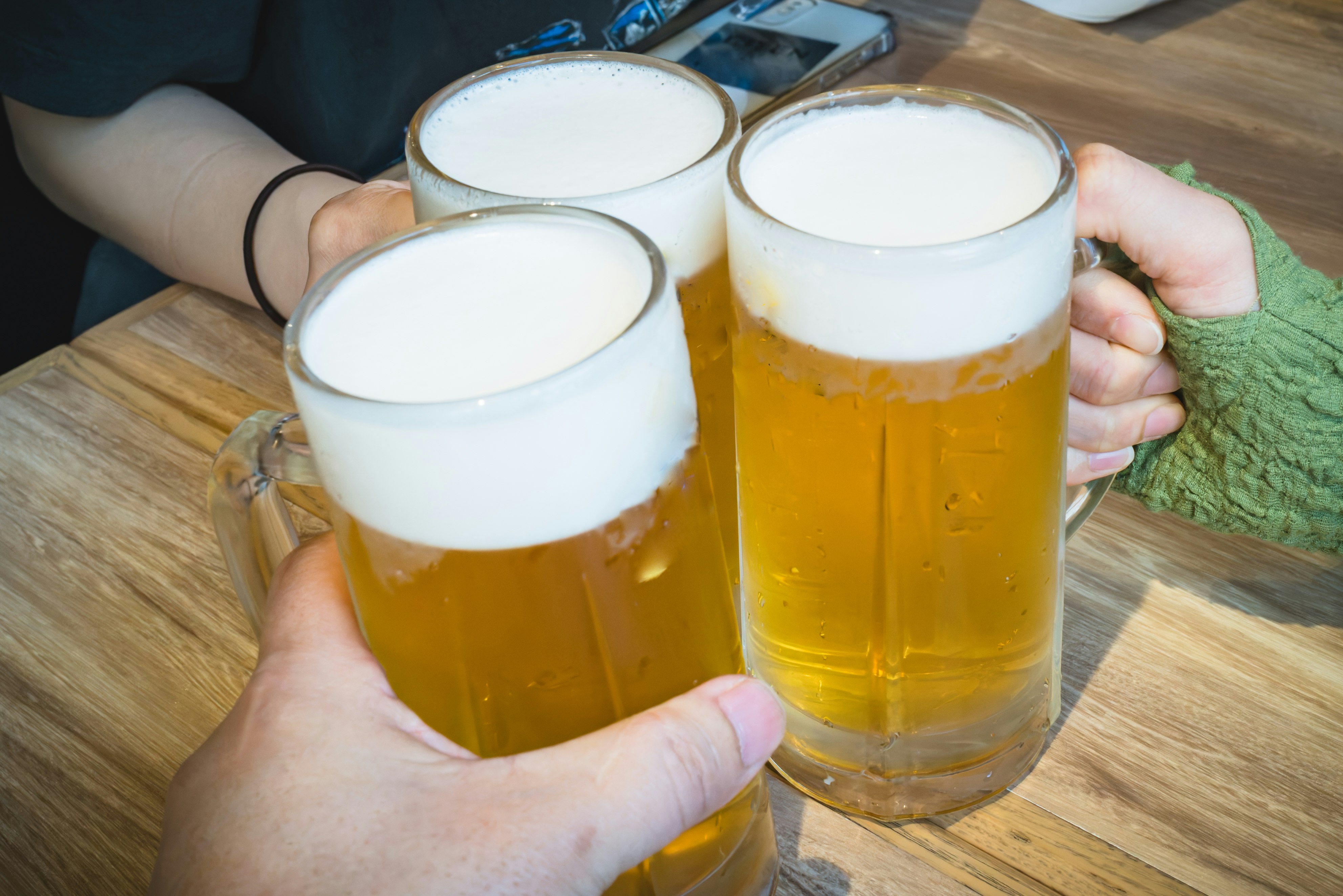 beer mugs clinking in a toast on a wooden table