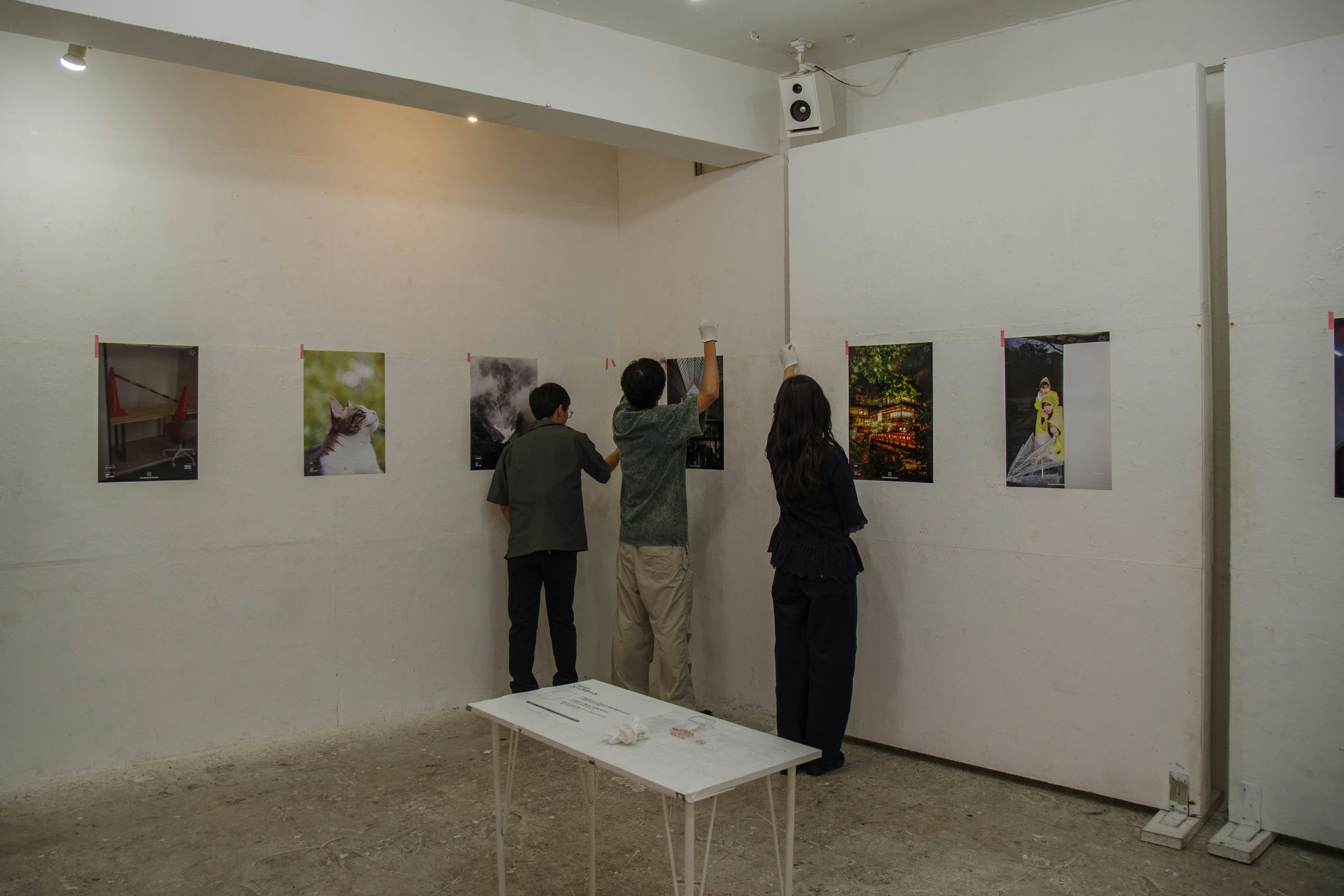 壁面に展示されたポスターと設営中の人物がいる東京のギャラリー