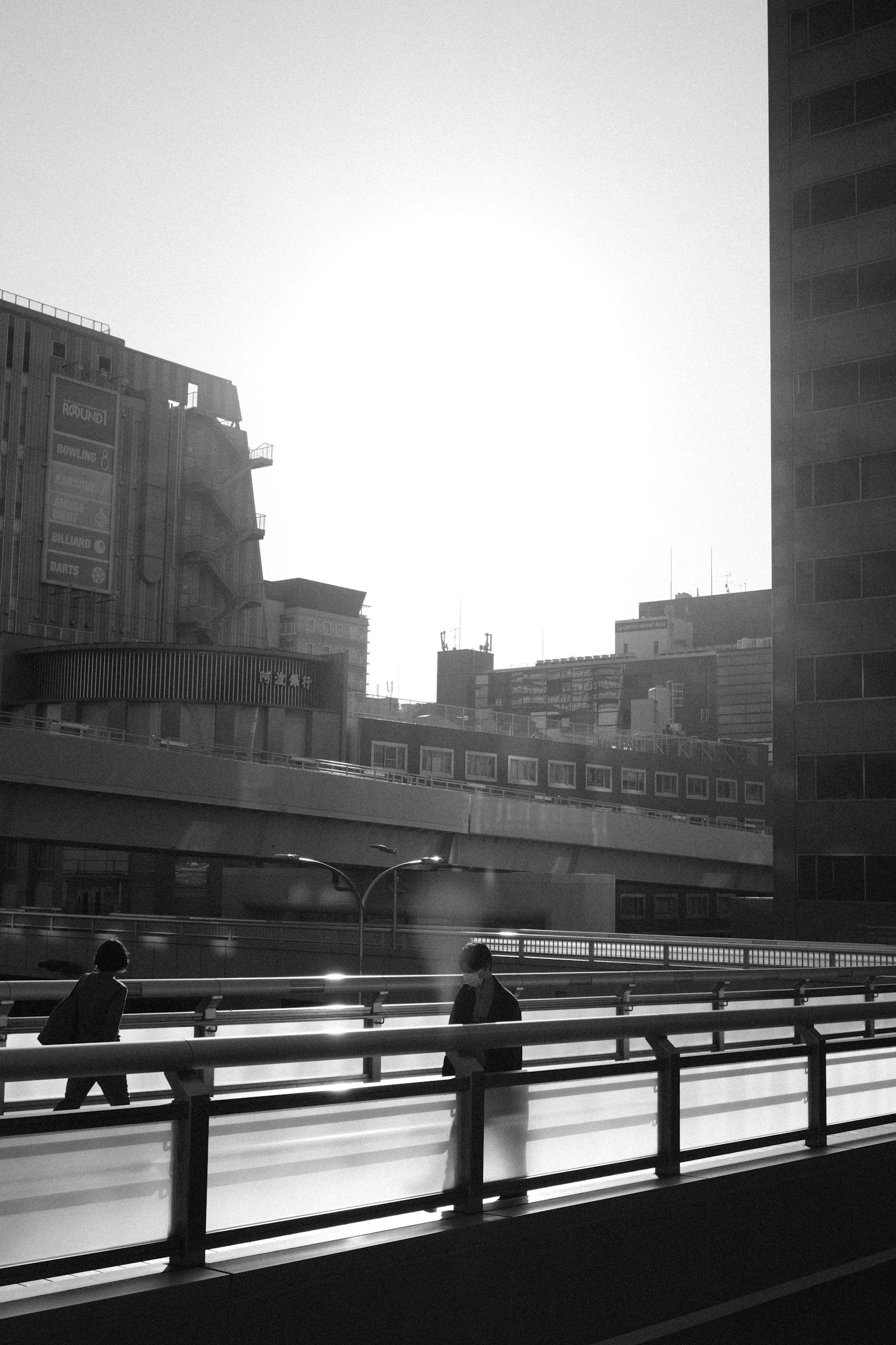 Silhouette di persone che camminano in un paesaggio urbano in bianco e nero con un tramonto sullo sfondo
