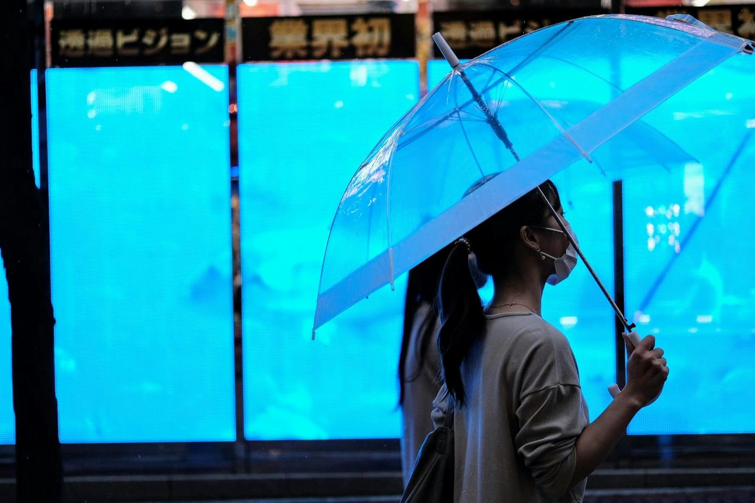 Người phụ nữ đi bộ vào ban đêm cầm ô màu xanh