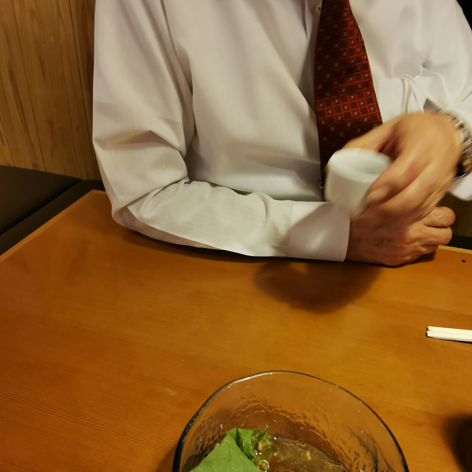 테이블에 있는 접시 옆에서 냅킨을 조정하는 흰색 셔츠를 입은 남성