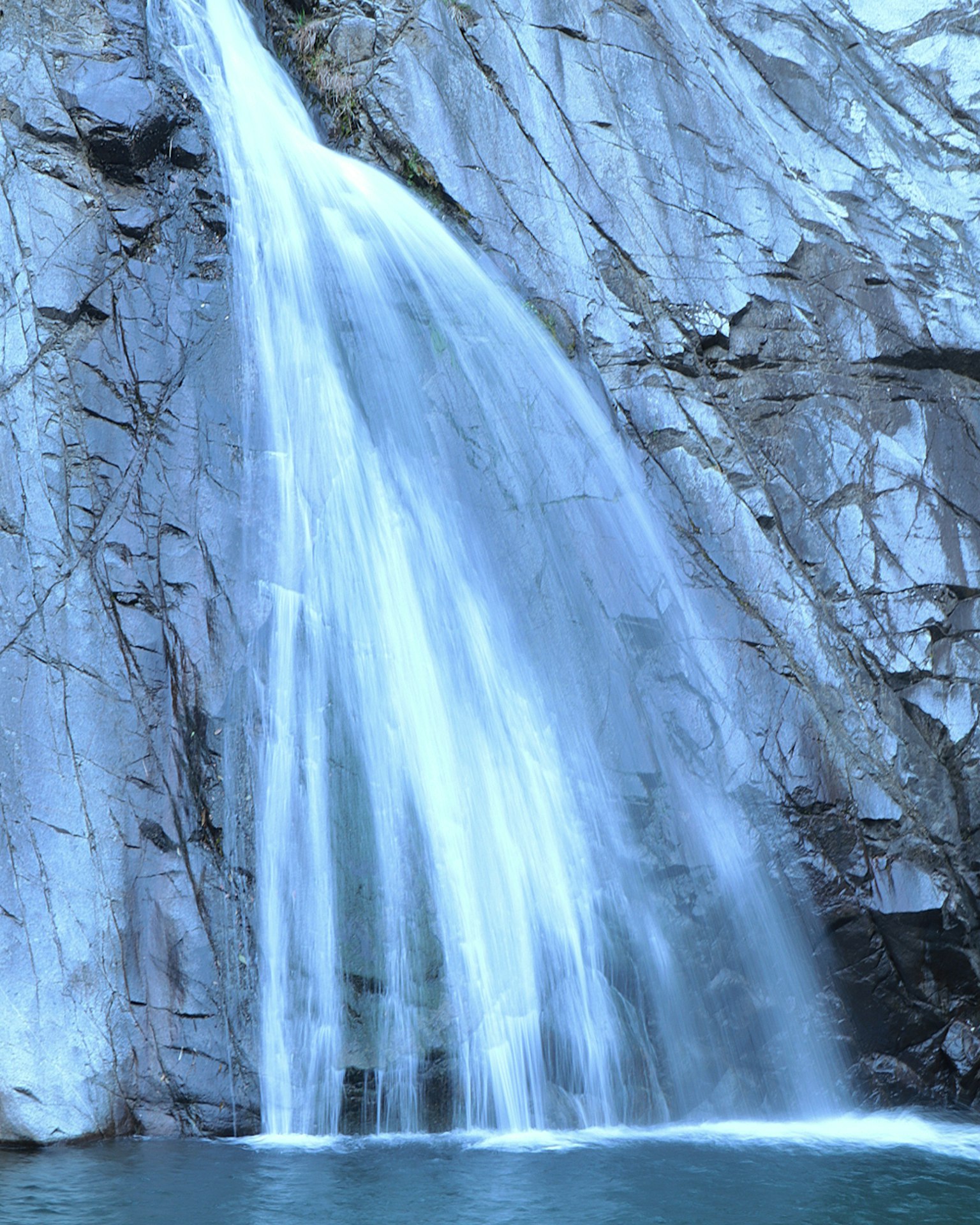 Imagen de una cascada con agua azul que fluye sobre acantilados rocosos
