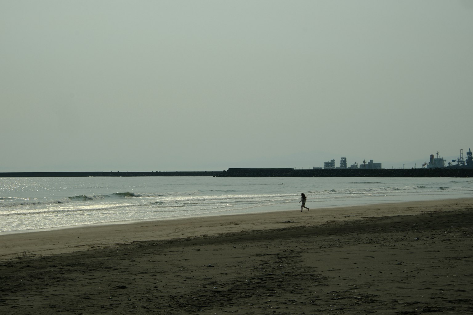 บุคคลเดียวยืนอยู่บนชายหาดที่เงียบสงบพร้อมกับคลื่นเบา