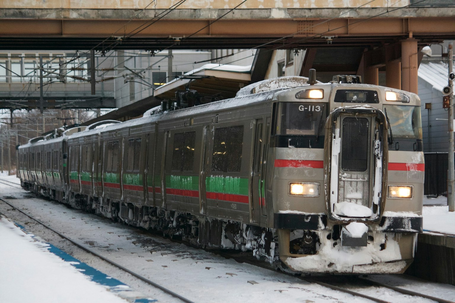 停靠在雪中車站的列車，具有綠色和紅色條紋